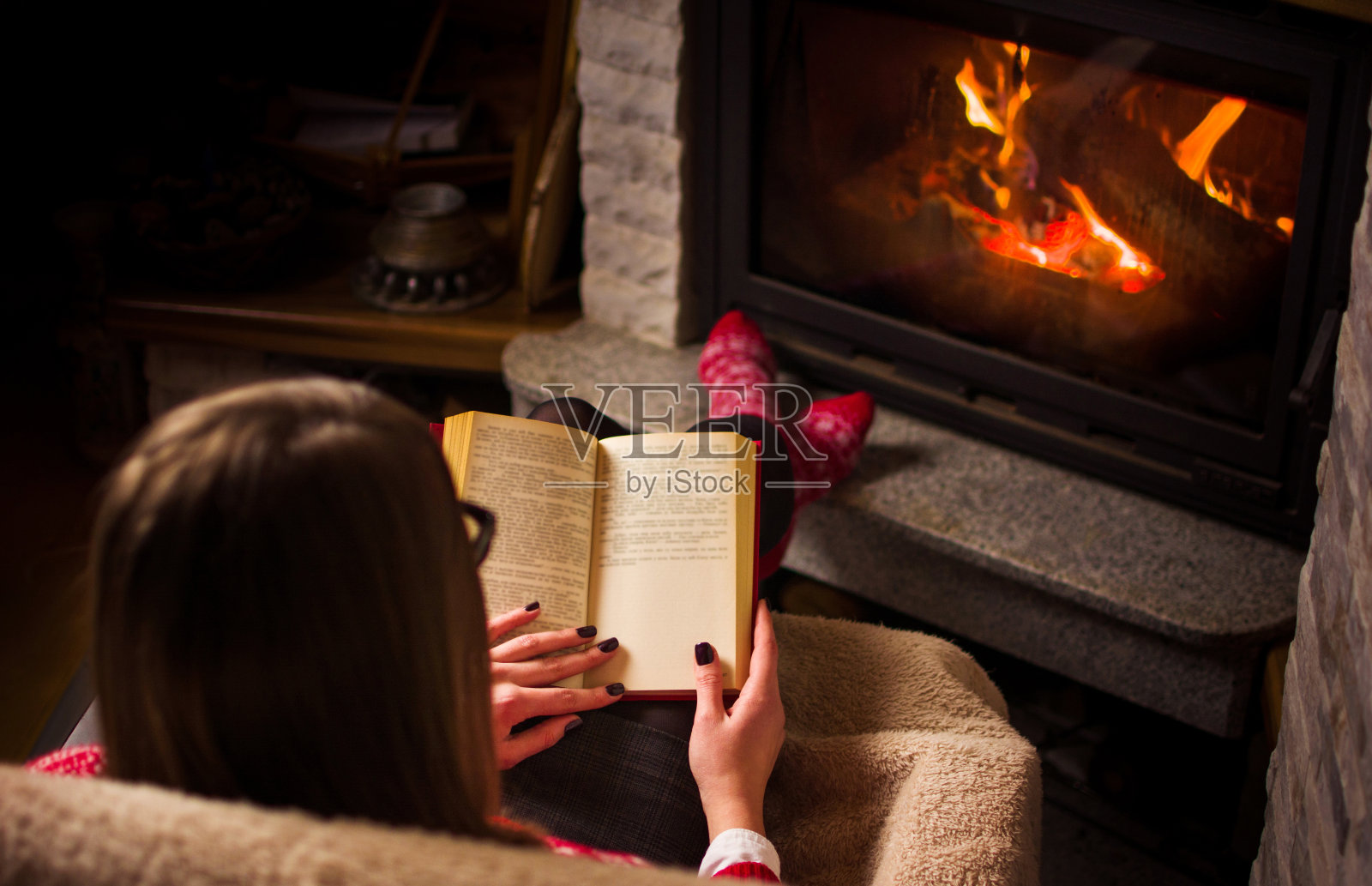 一个女人在壁炉边看书照片摄影图片
