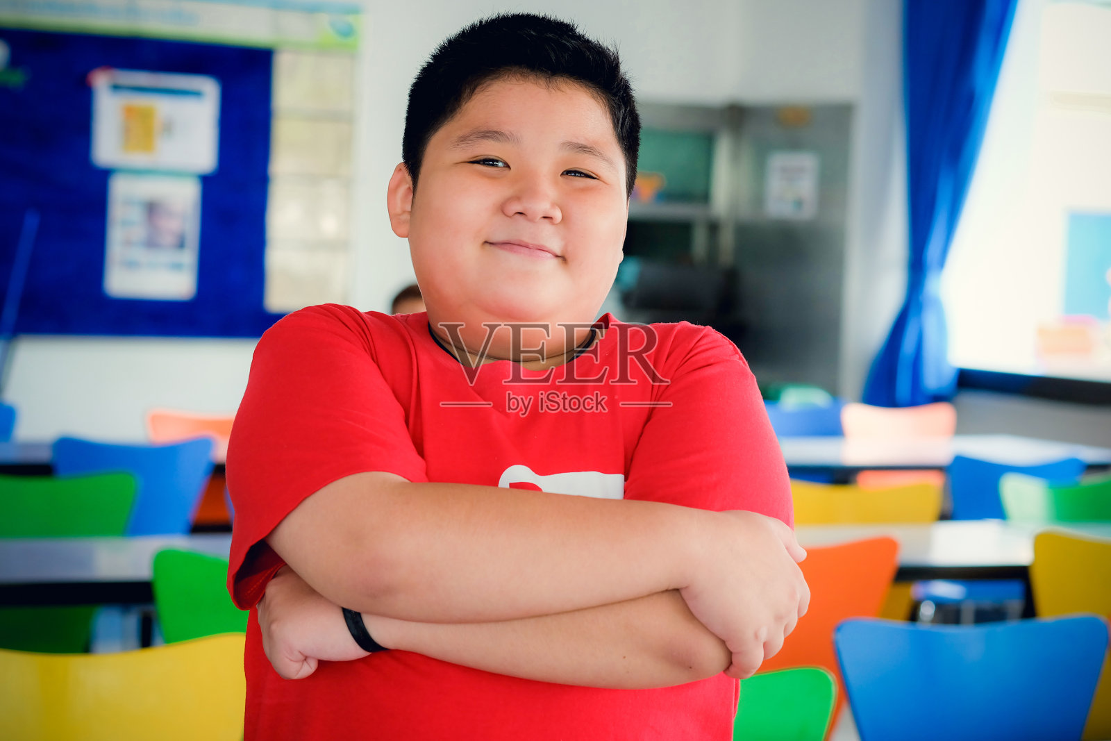 亚洲肥胖男孩站在交叉的胳膊和可爱的微笑照片摄影图片