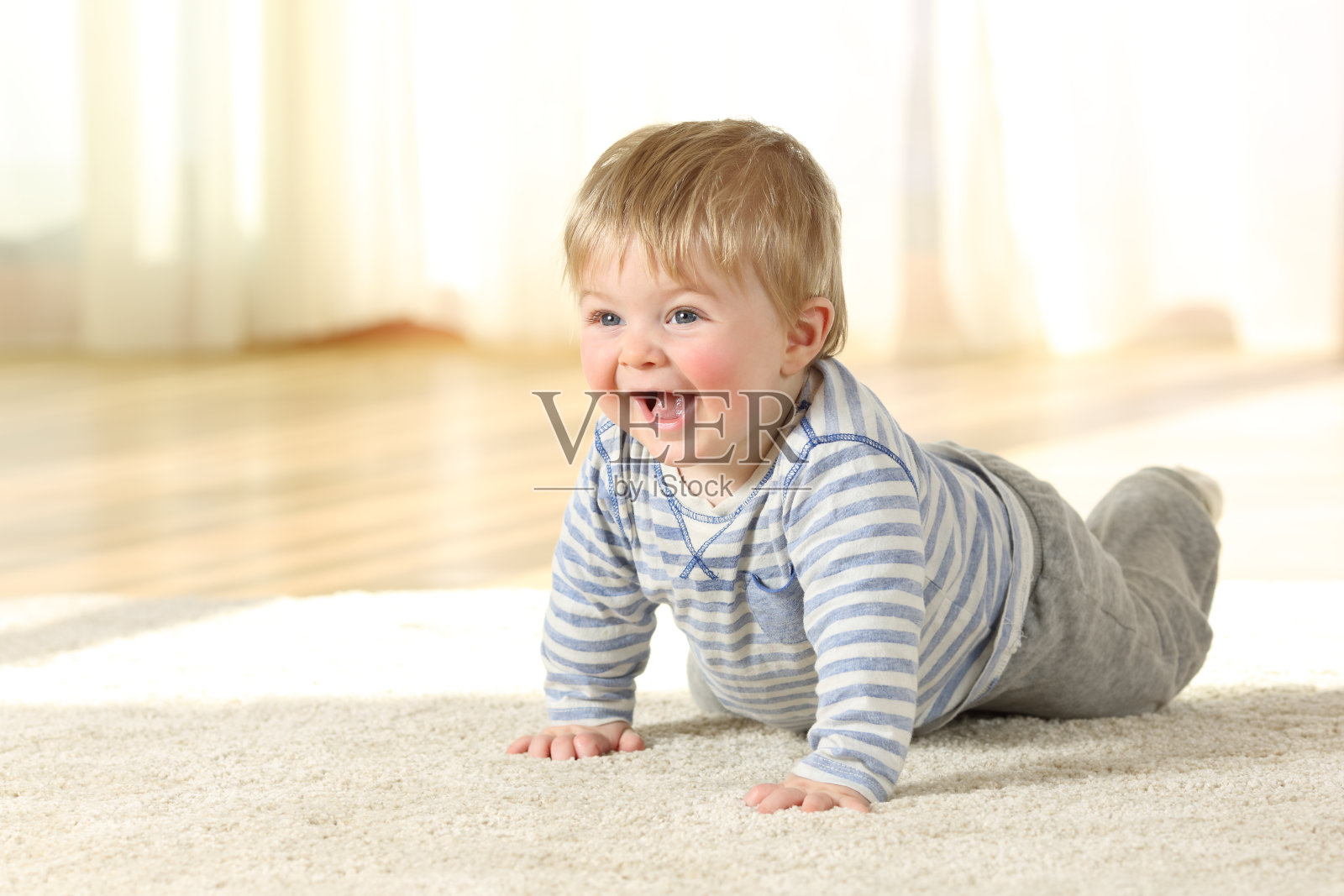 快乐的宝宝在家里的地毯上爬行照片摄影图片