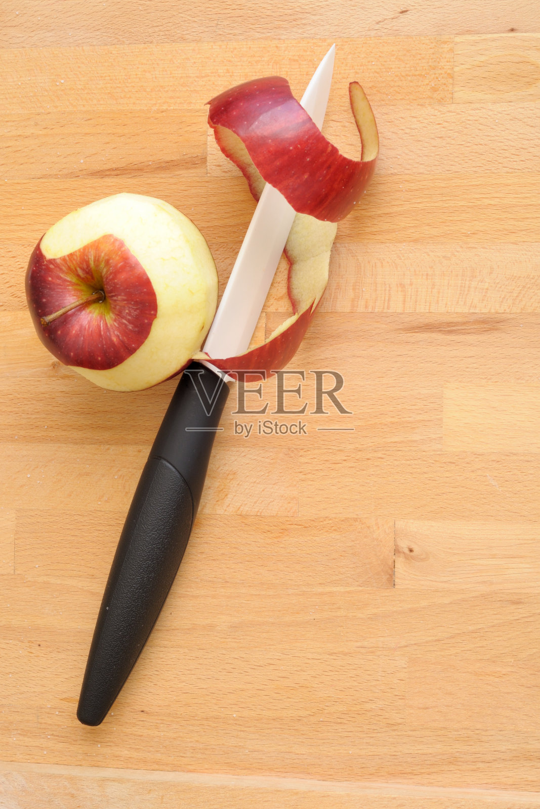 白色陶瓷刀削红苹果，垂直照片摄影图片