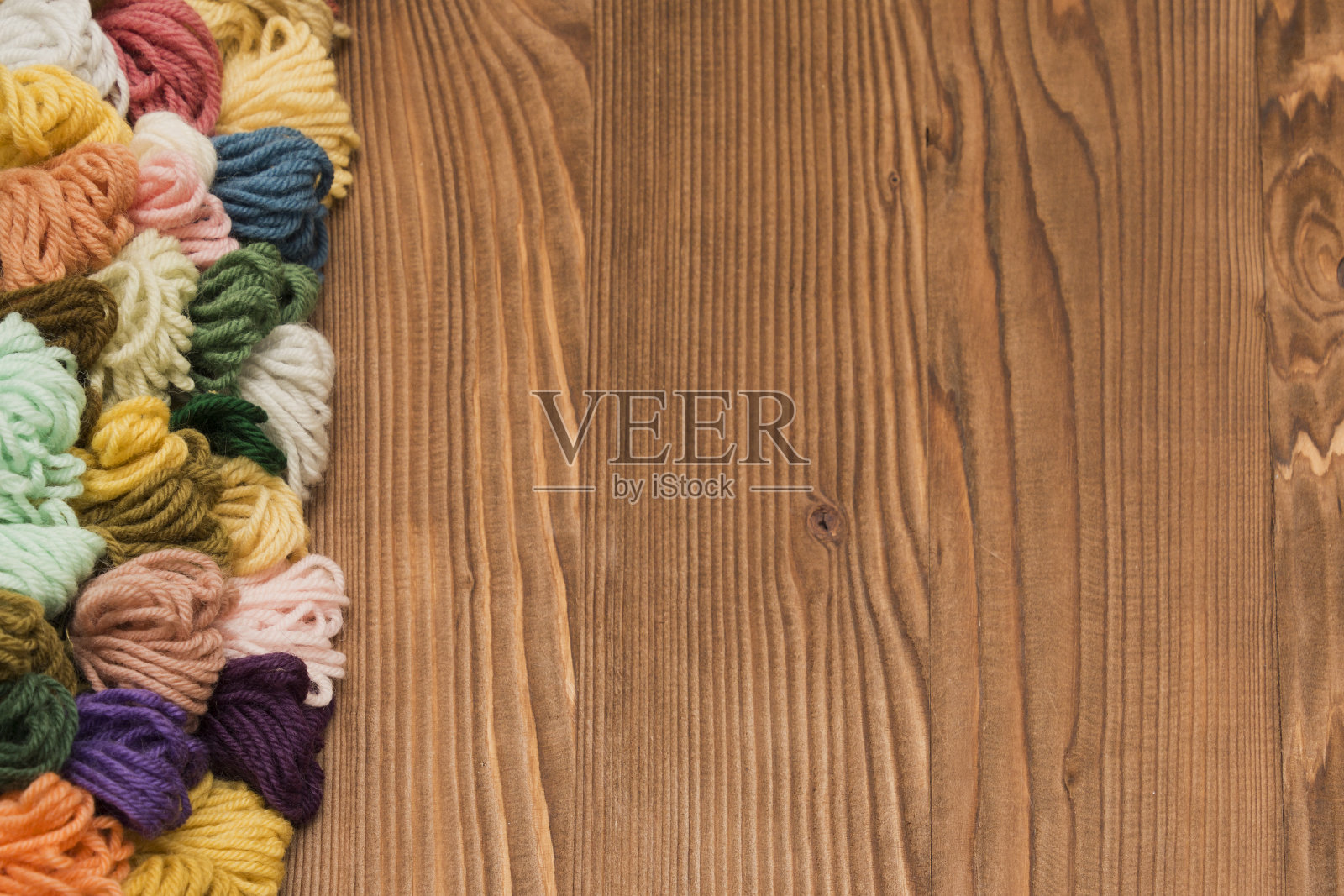 彩色的编织线在木制的背景上照片摄影图片