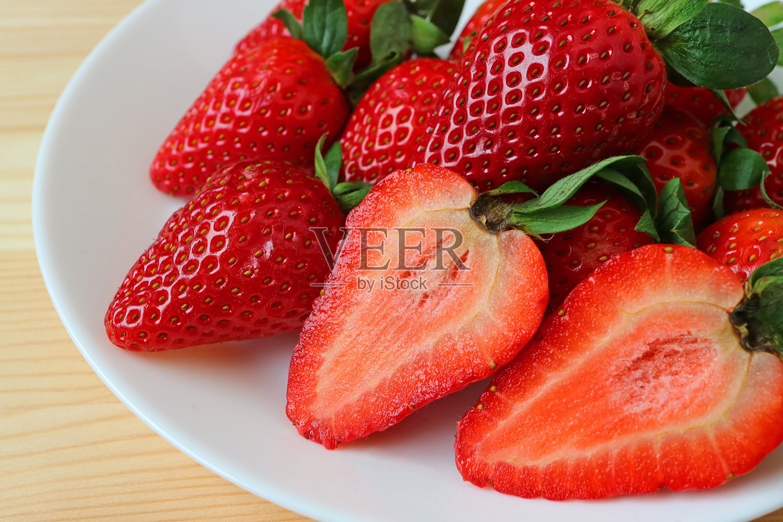 整个水果和横切面充满活力的红色新鲜草莓水果在白色盘子，微距拍摄水果的质地照片摄影图片