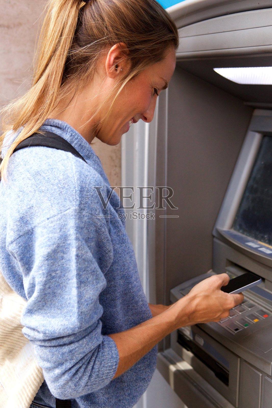 年轻女子用手机通过银行自动取款机照片摄影图片