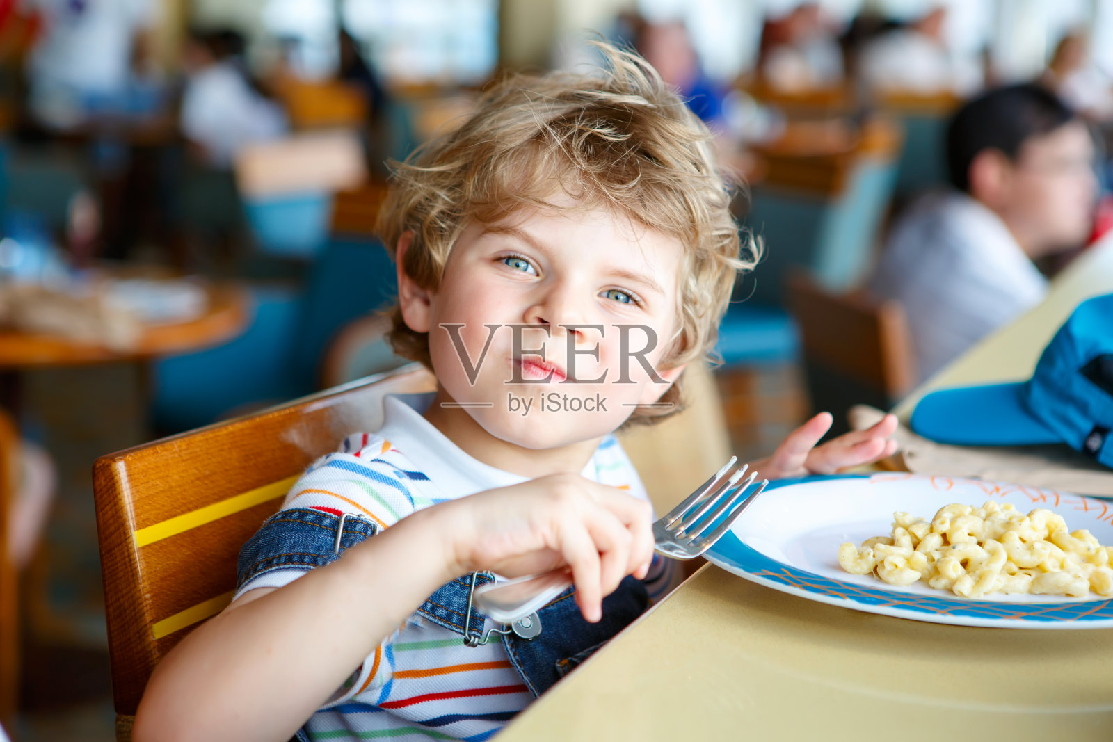 可爱健康的学前班男孩坐在学校食堂吃意大利面照片摄影图片
