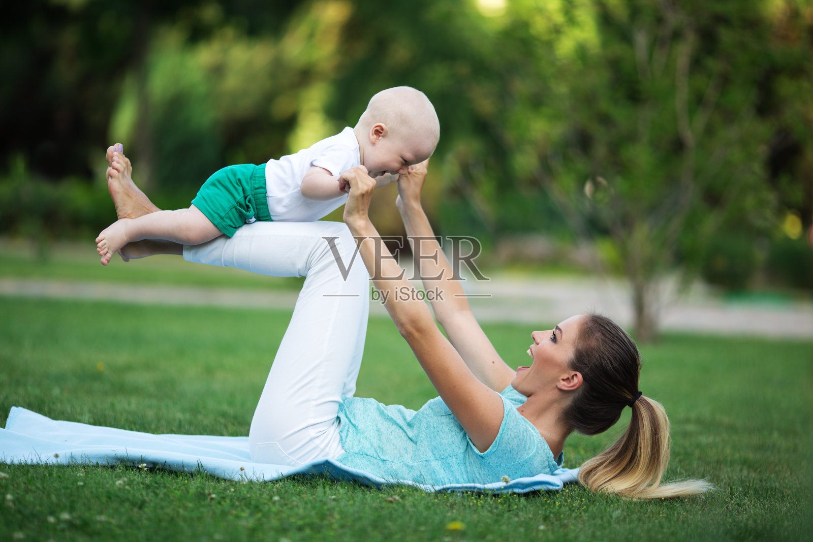 爱运动的快乐妈妈正带着小儿子在草坪上锻炼。运动理念，夏季时间照片摄影图片