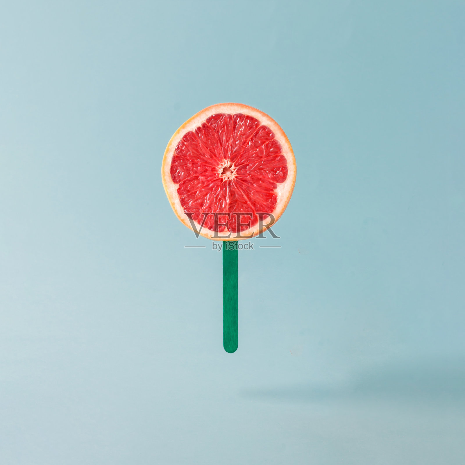 红色葡萄柚和冰淇淋棒在柔和的蓝色背景。食品创意概念。照片摄影图片