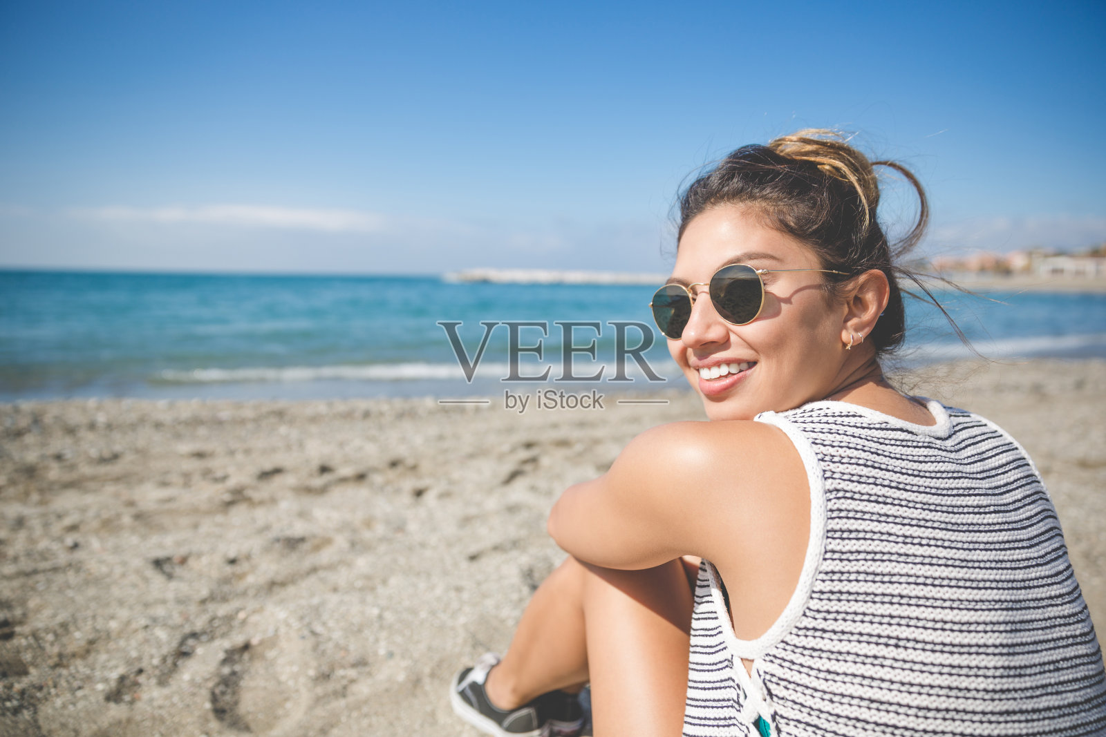 年轻漂亮的女人坐在海滩上微笑照片摄影图片