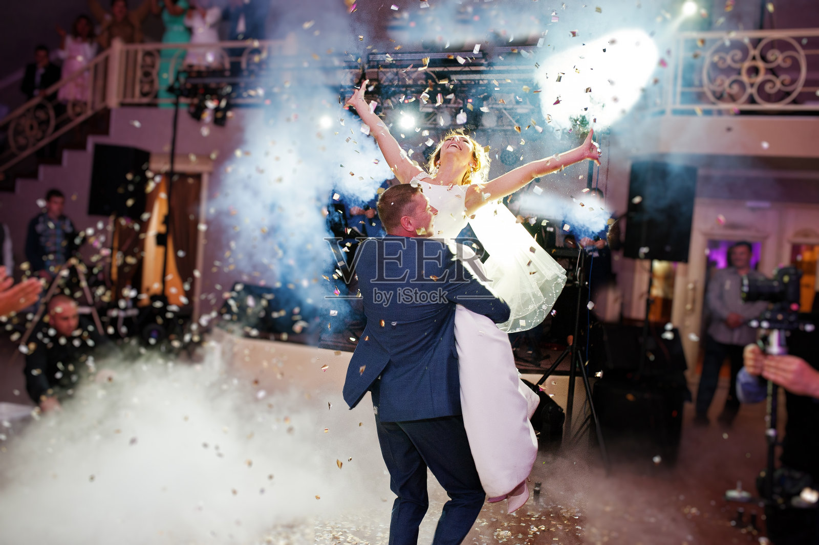 新婚夫妇在他们的婚礼上以浓重的烟雾和彩灯为背景跳舞。照片摄影图片