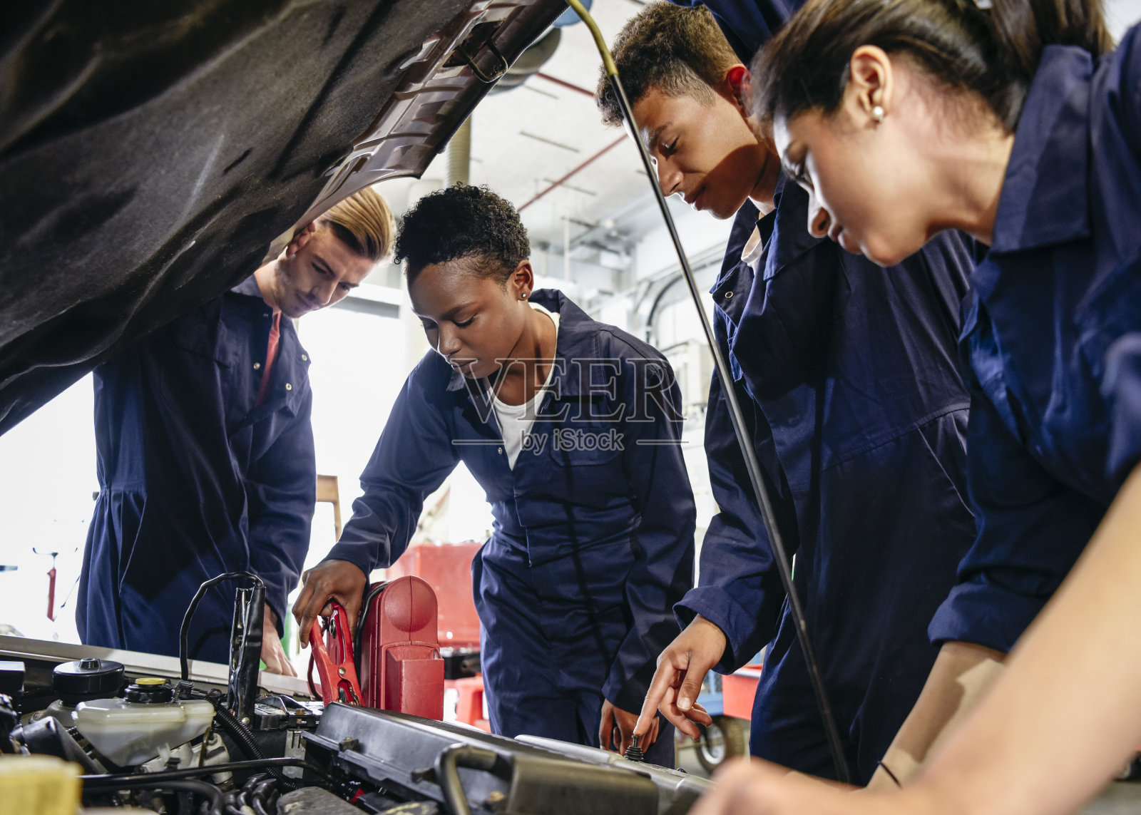 一组学生机械师在汽车发动机罩上工作照片摄影图片