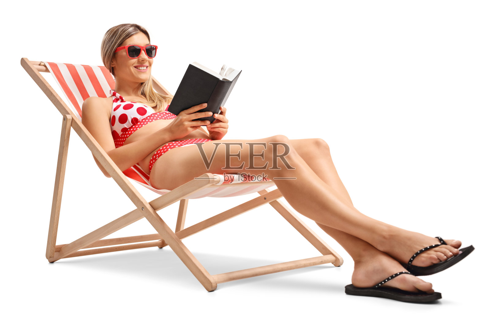 一个年轻的女人在躺椅上看书照片摄影图片
