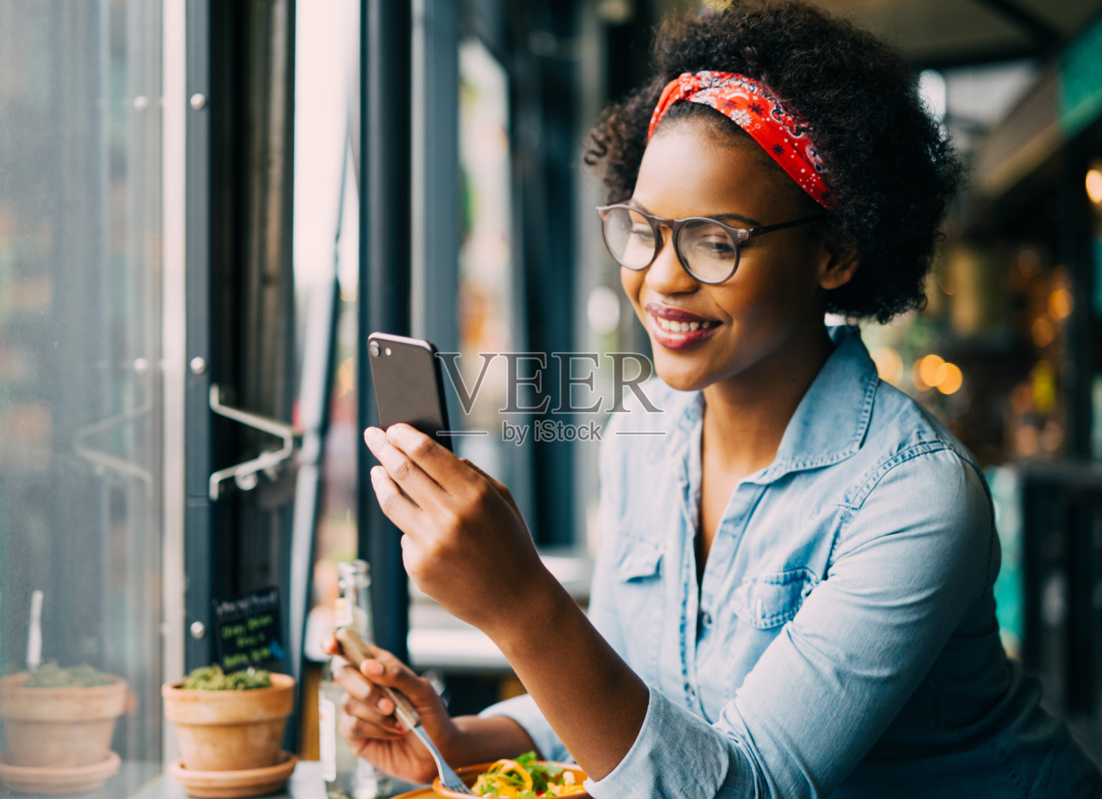 一个微笑的女人在小酒馆吃饭时看短信照片摄影图片