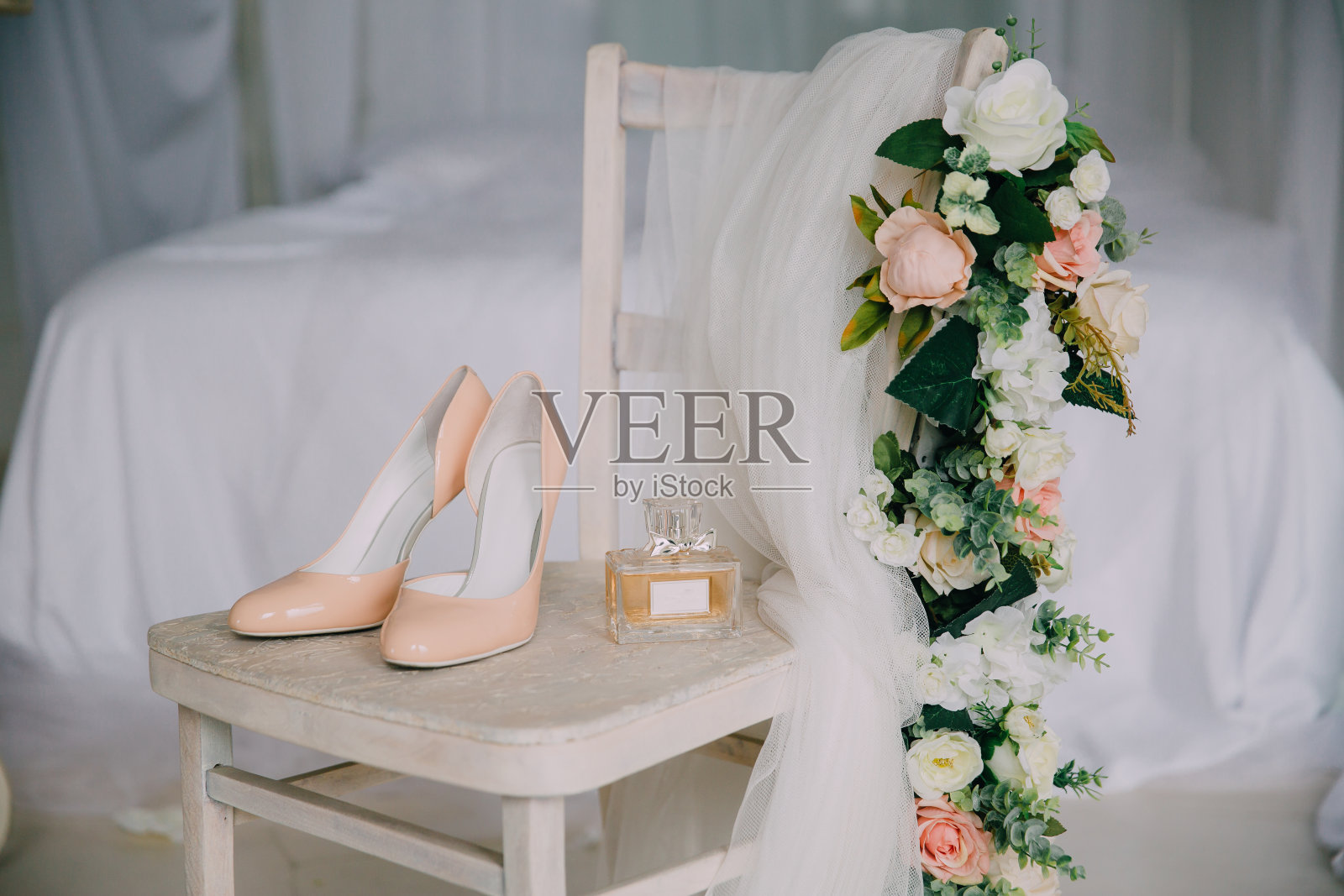 白色的椅子上放着新娘的装饰品，还有花，香水鞋。服装的概念照片摄影图片