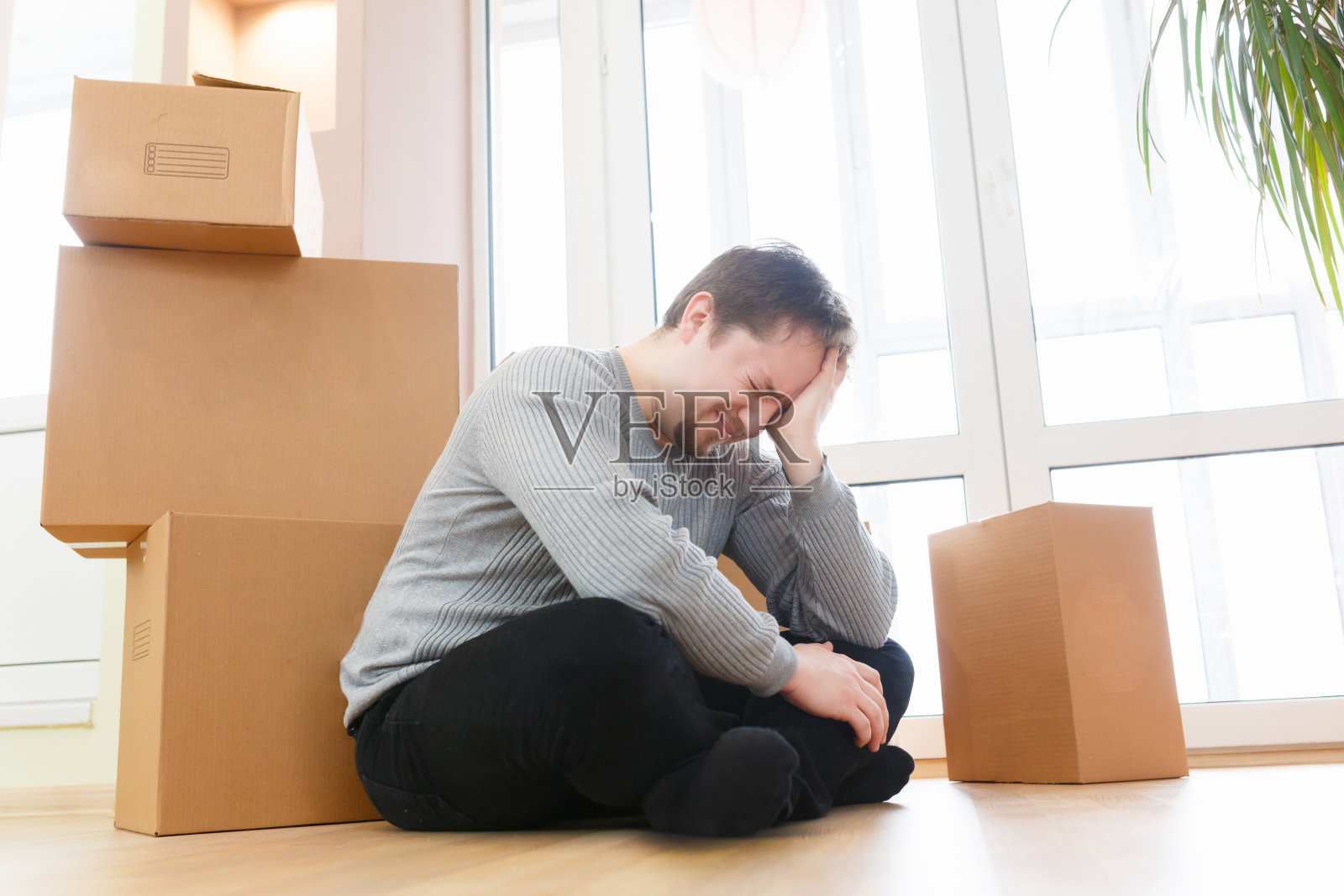 担心和沮丧的年轻人坐在包装盒子的房子出售照片摄影图片