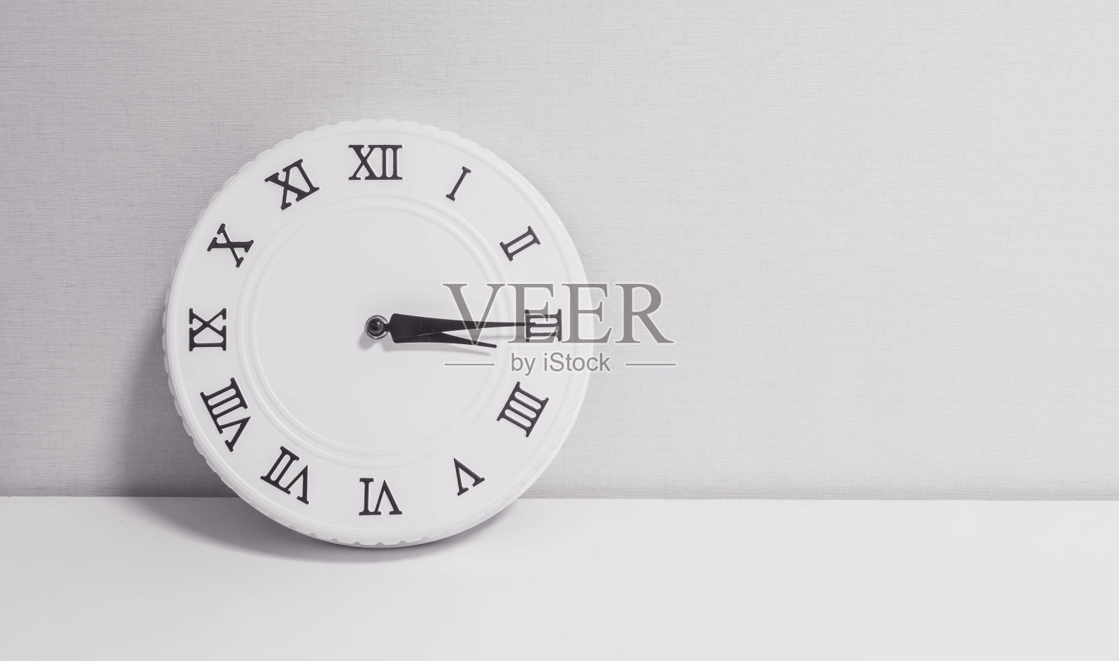 特写白色时钟装饰显示三点一刻或下午3:15在白色的木桌和壁纸纹理背景在黑白色调与复制空间照片摄影图片