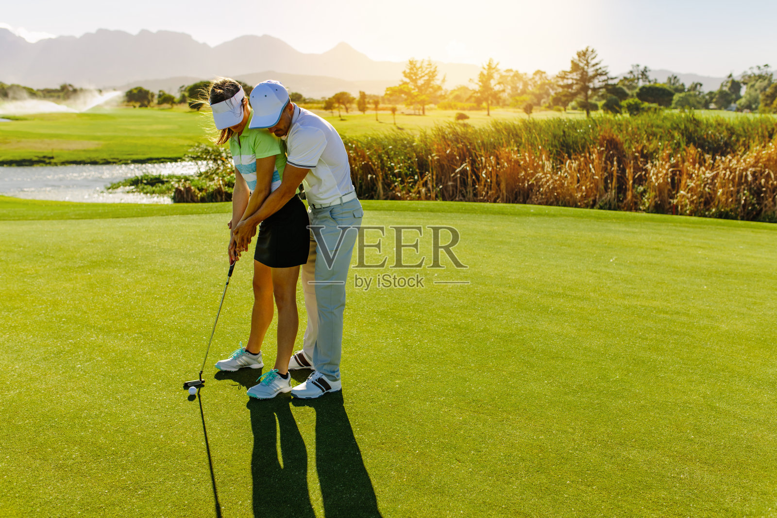 男教练教女人打高尔夫球照片摄影图片