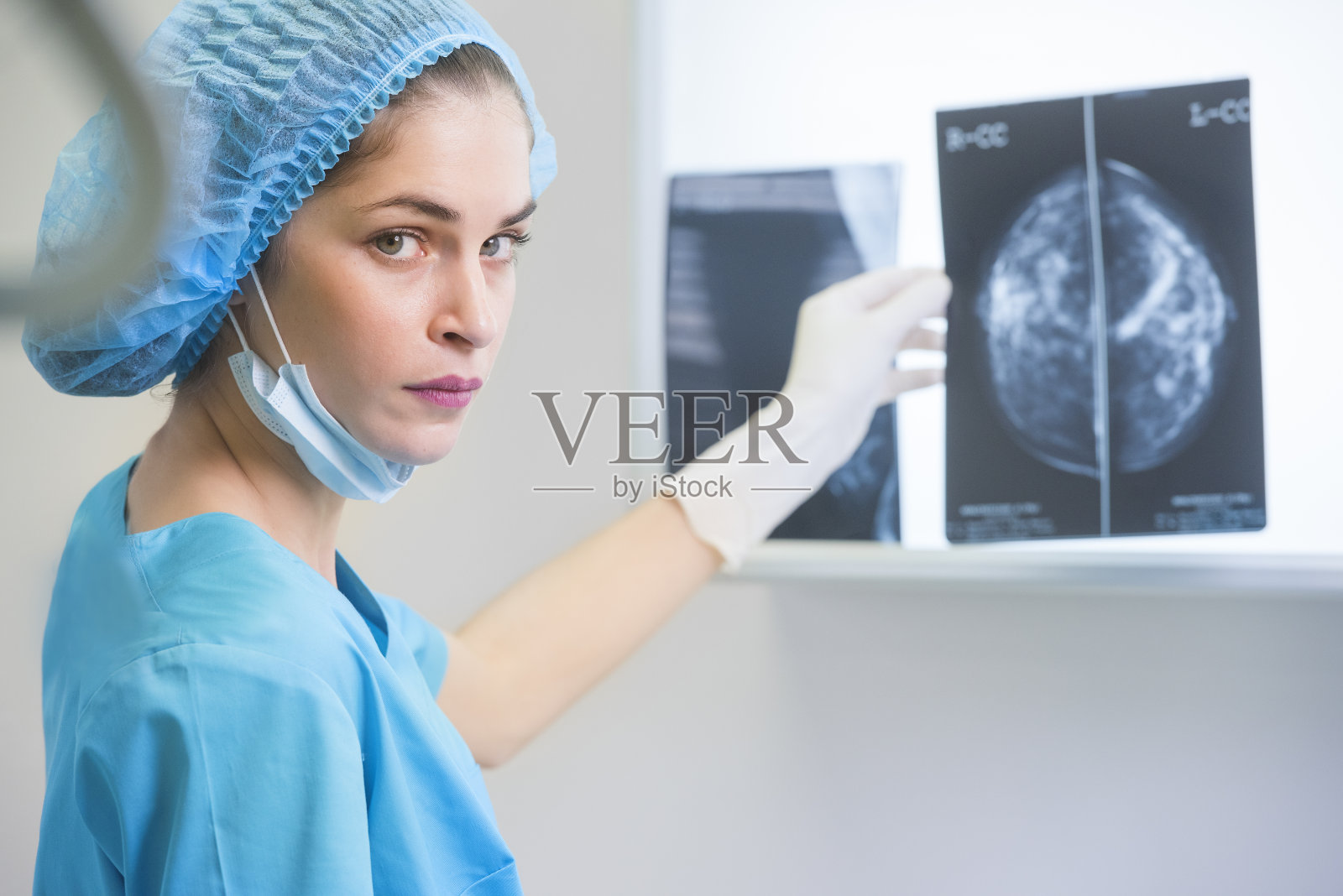 身着手术服的女医生或护士正拿着一张乳房x光片站在x光照明灯前照片摄影图片