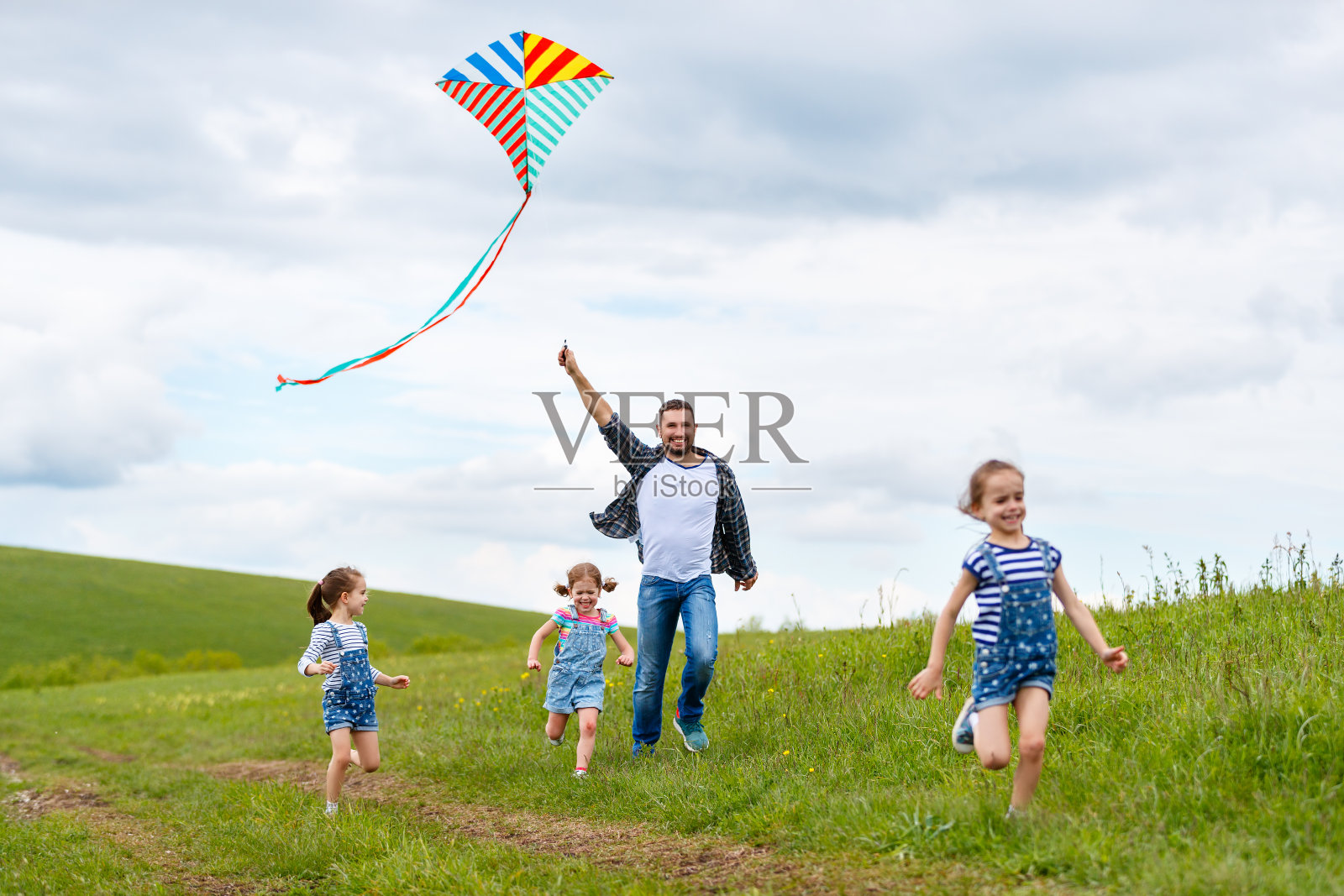幸福的家庭父亲和孩子们在草地上追风筝照片摄影图片