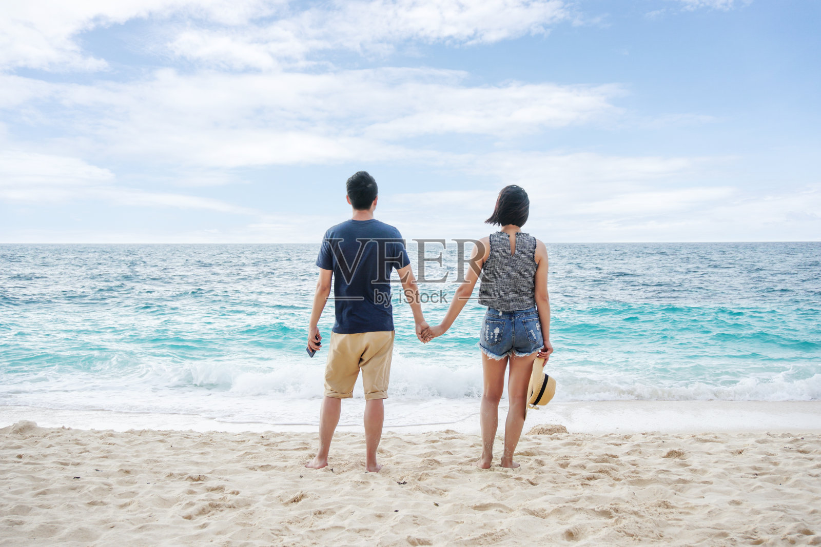 年轻夫妇手牵着手在海滩上散步照片摄影图片
