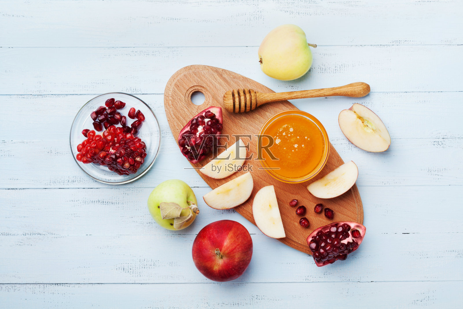 犹太新年的餐桌上摆满了传统食物。蜂蜜，苹果片和石榴。平的。照片摄影图片