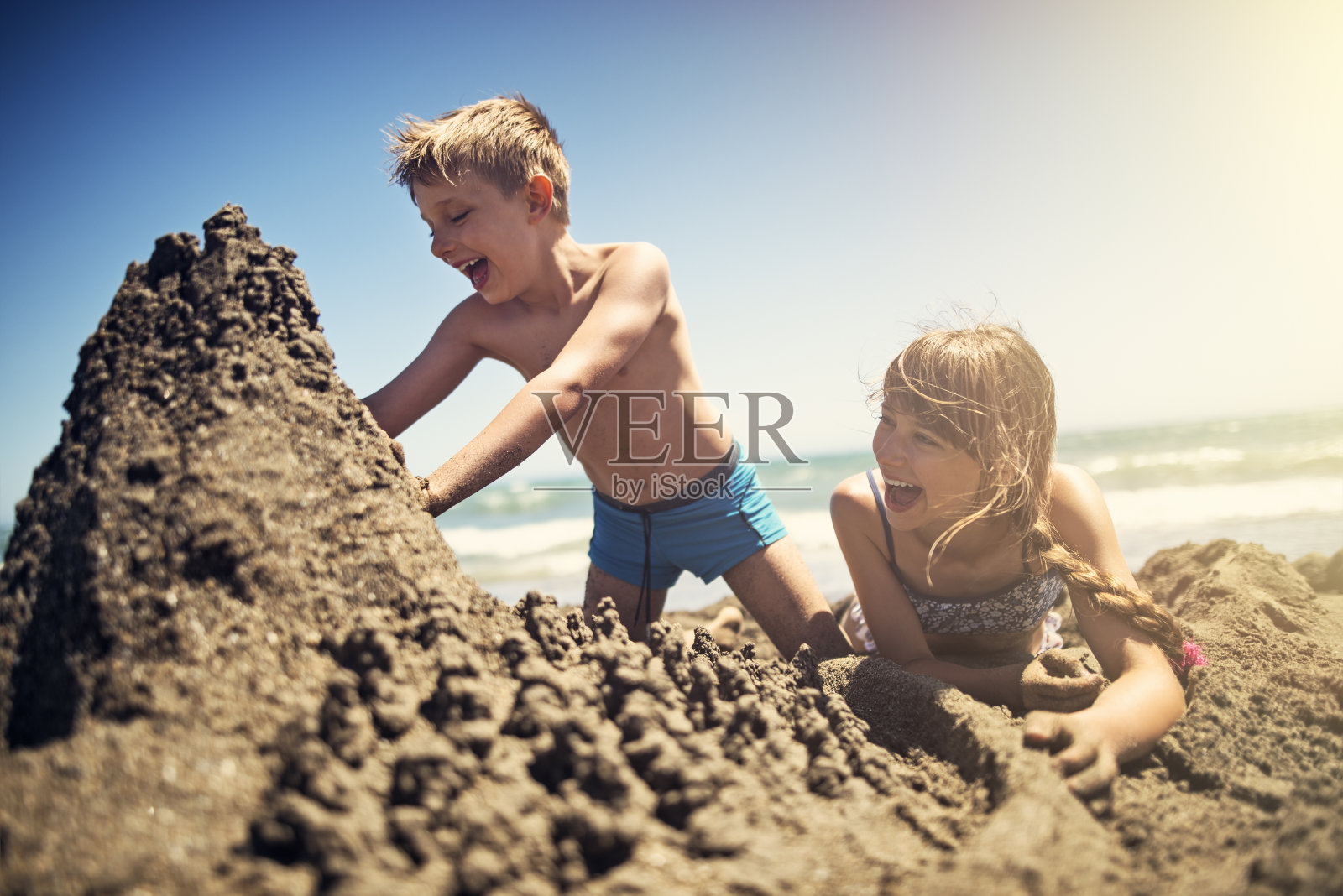 哥哥和妹妹在海滩上建造沙堡照片摄影图片