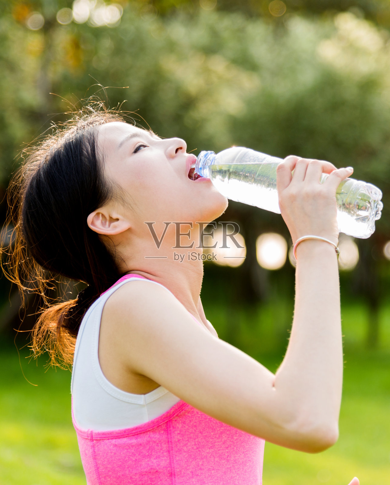 年轻女子在公园喝瓶装水照片摄影图片
