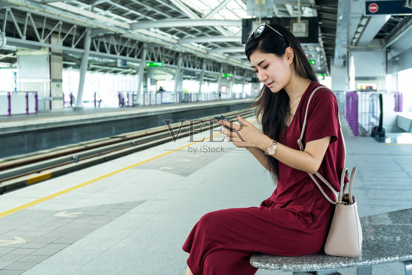 亚洲女性乘客与休闲服装通过智能手机使用社交网络在BTS轻轨或捷运地铁在大城市旅行，生活方式和交通理念照片摄影图片