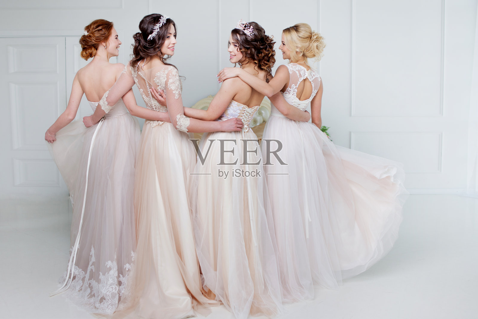 新娘在婚礼沙龙。四个美丽的女孩相互拥抱着。背部，特写蕾丝裙照片摄影图片