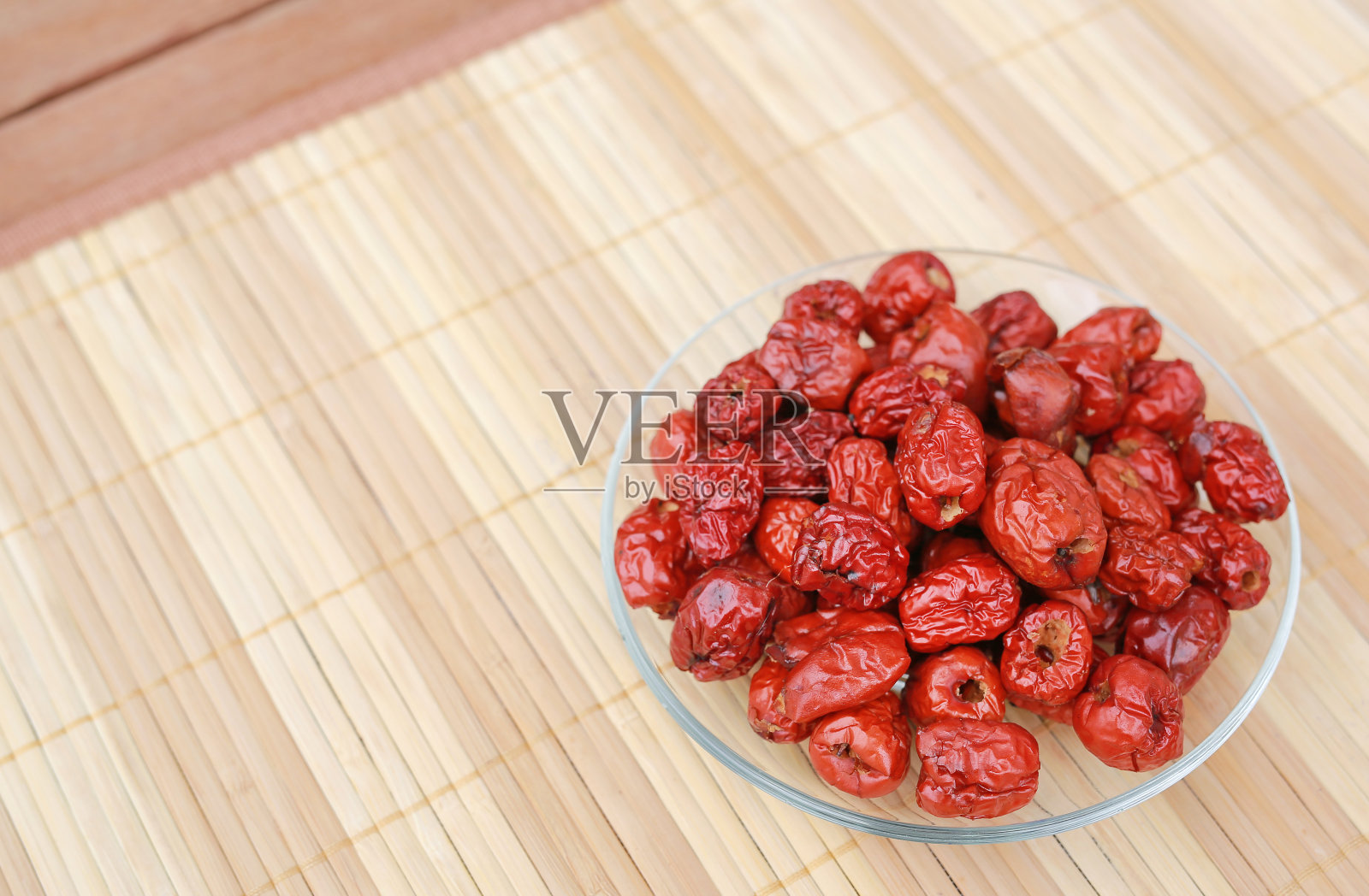 大枣、红枣等水果放在盘子上，以木色为背景，留有复制空间。照片摄影图片