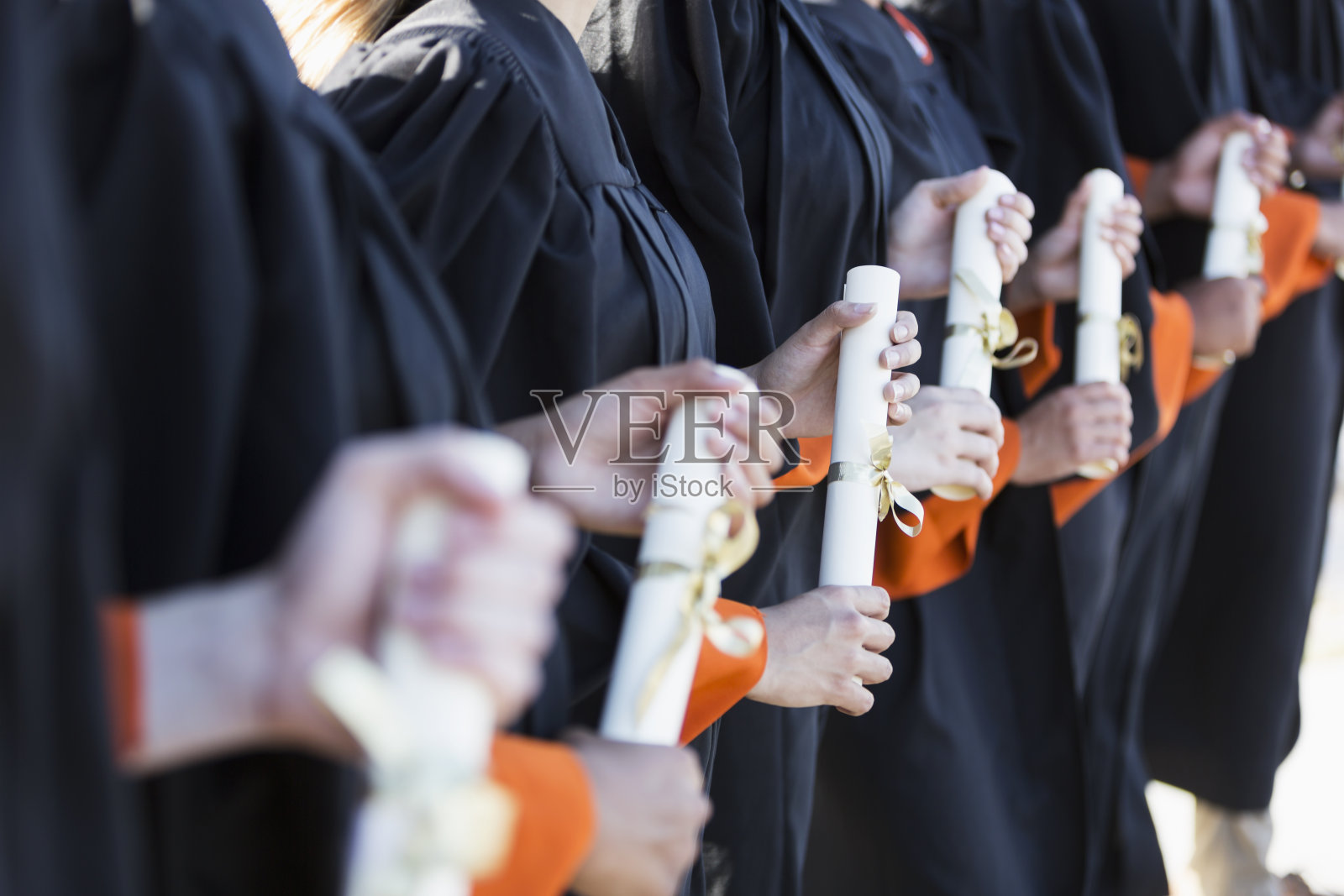 多民族的青少年毕业生戴着帽子，穿着长袍照片摄影图片