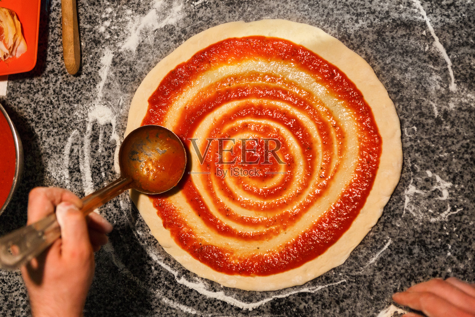 厨师亲手将番茄酱抹在披萨底上照片摄影图片