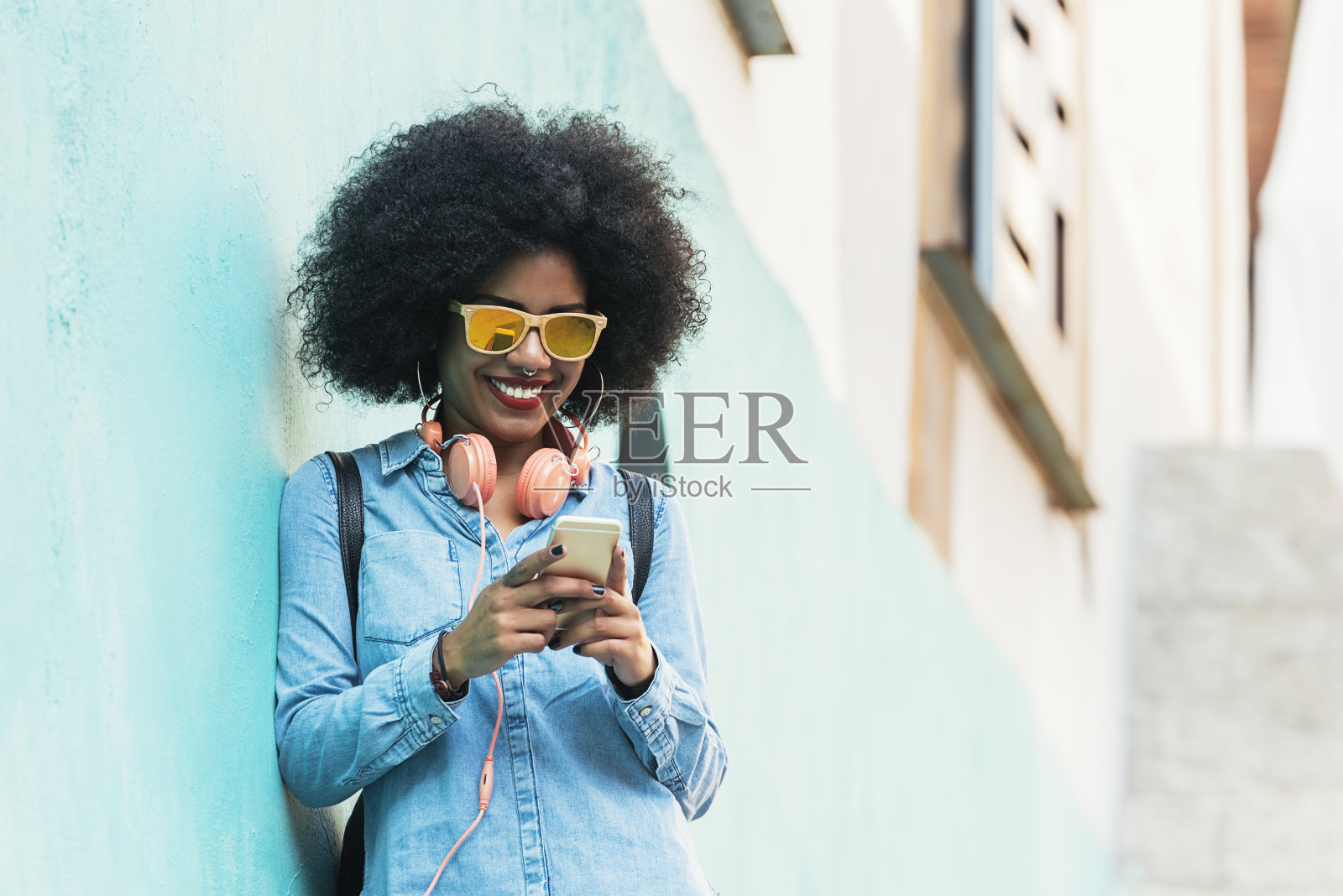 美丽的非洲裔美国女人在街上用手机。照片摄影图片