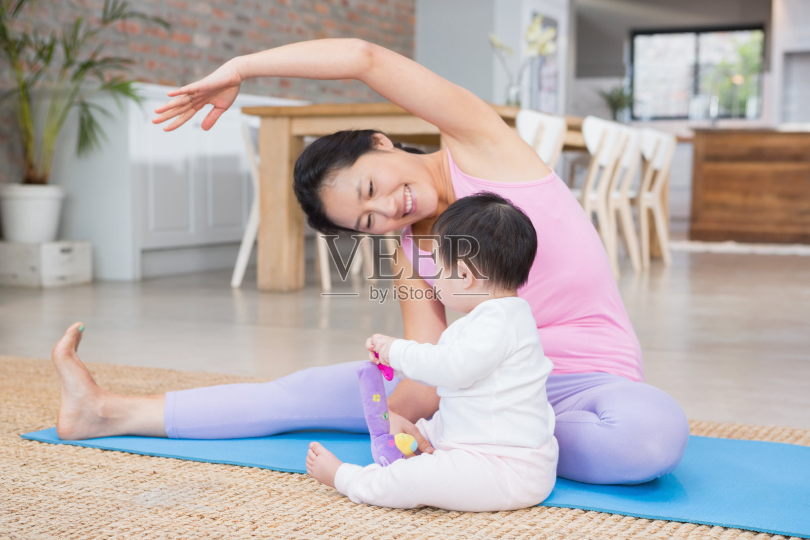 快乐的妈妈在垫子上做瑜伽，同时看着宝贝女儿照片摄影图片