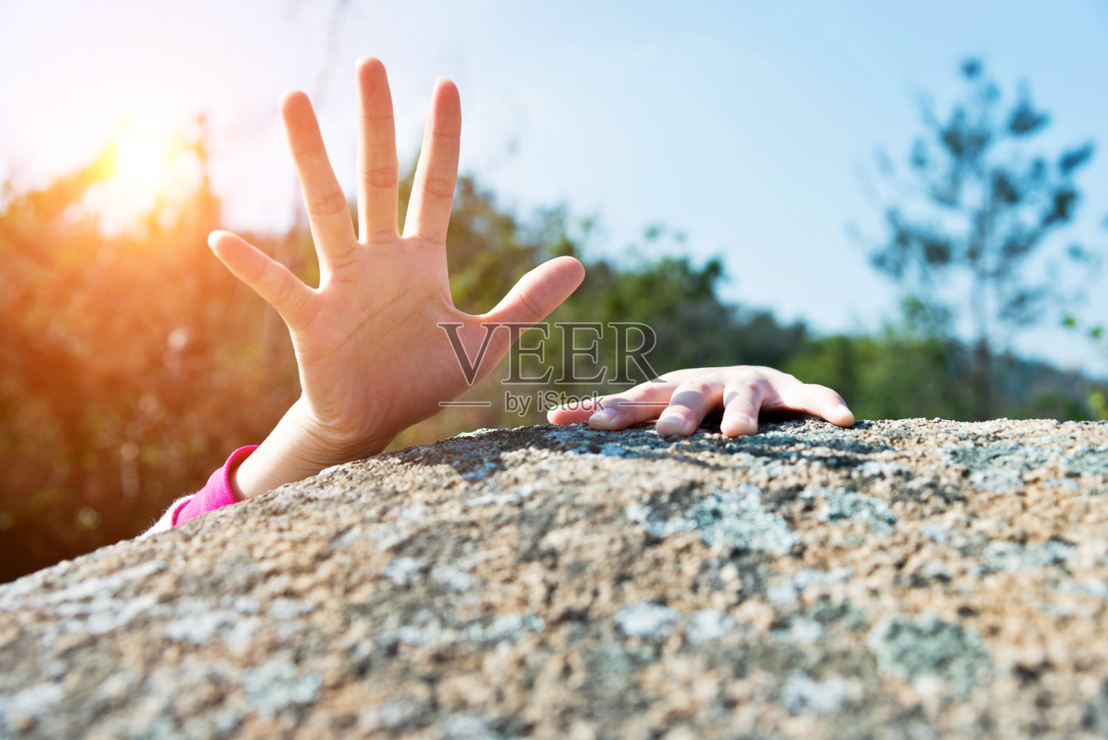 女人伸手在岩石上求助照片摄影图片
