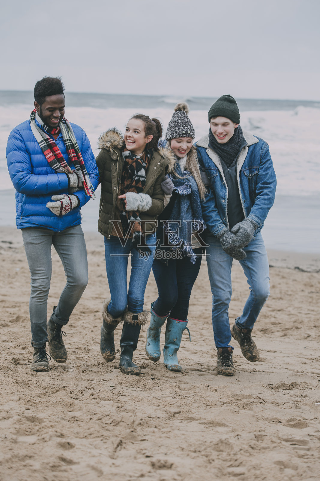 朋友们在冬天的海滩上散步照片摄影图片