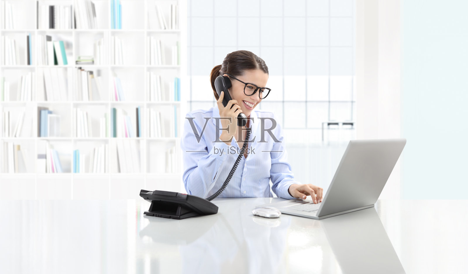 微笑的女人在办公室打电话和使用电脑坐在大桌面照片摄影图片