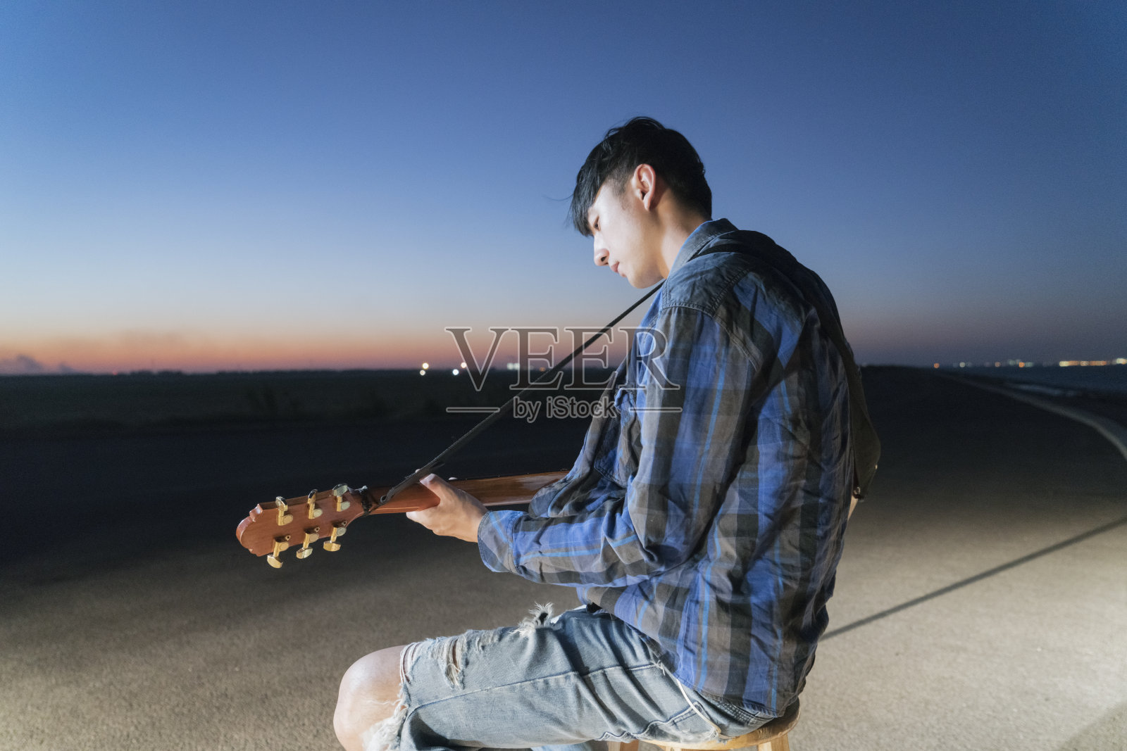 年轻的吉他手在城市海滨弹奏原声吉他照片摄影图片