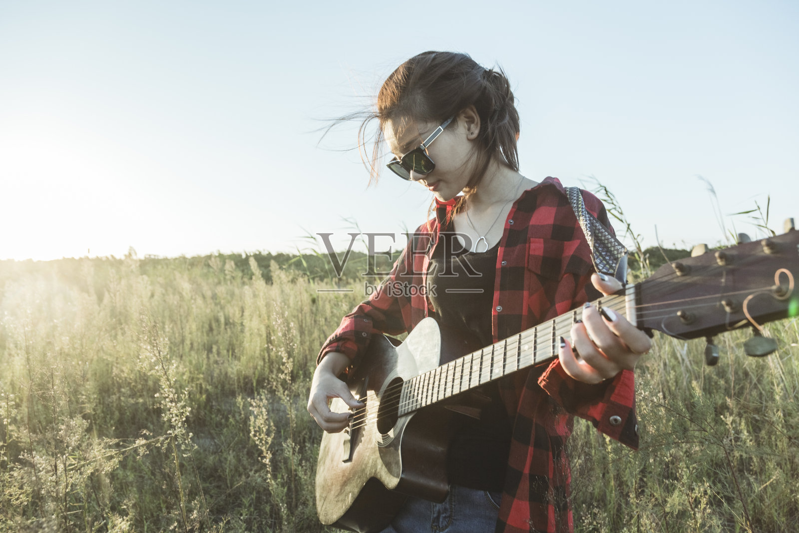 女人的手在田野里弹吉他的特写照片摄影图片