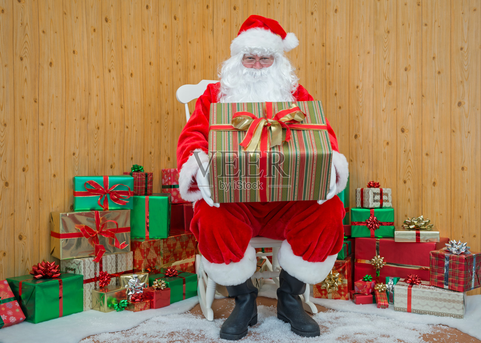 圣诞老人在他的洞穴里拿着一个包装好的礼物照片摄影图片