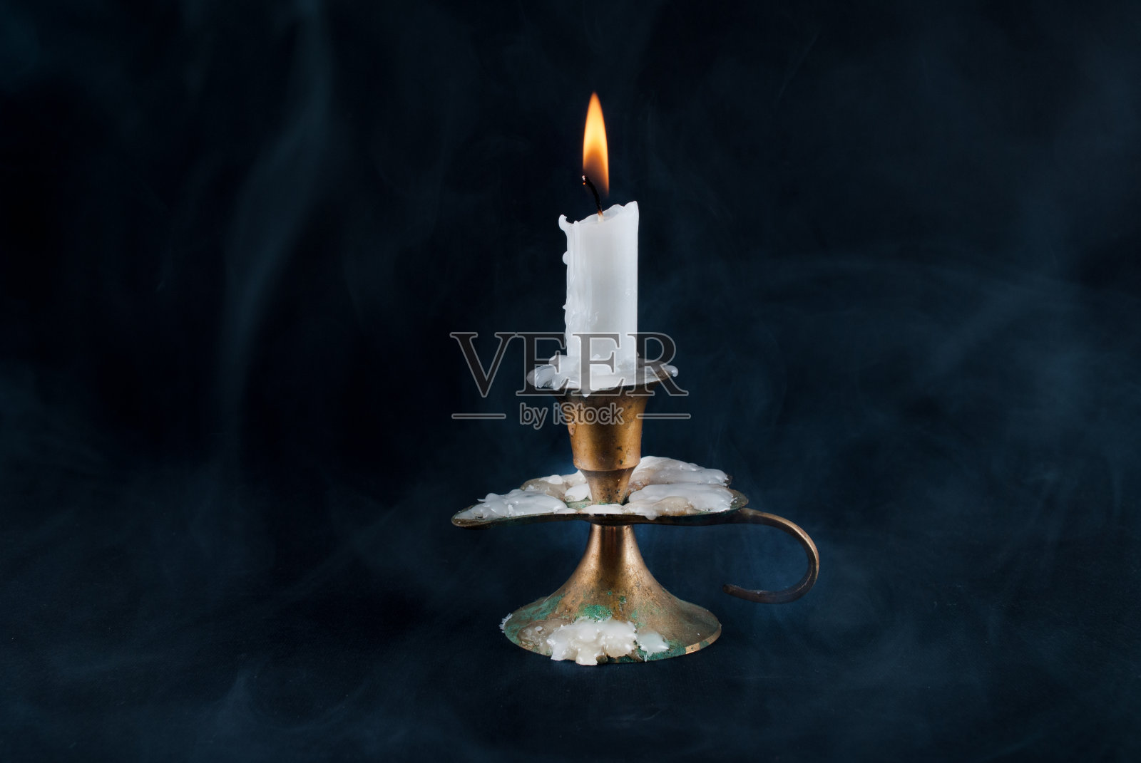 蜡烛在旧烛台和烟在背景孤立在黑暗的背景照片摄影图片
