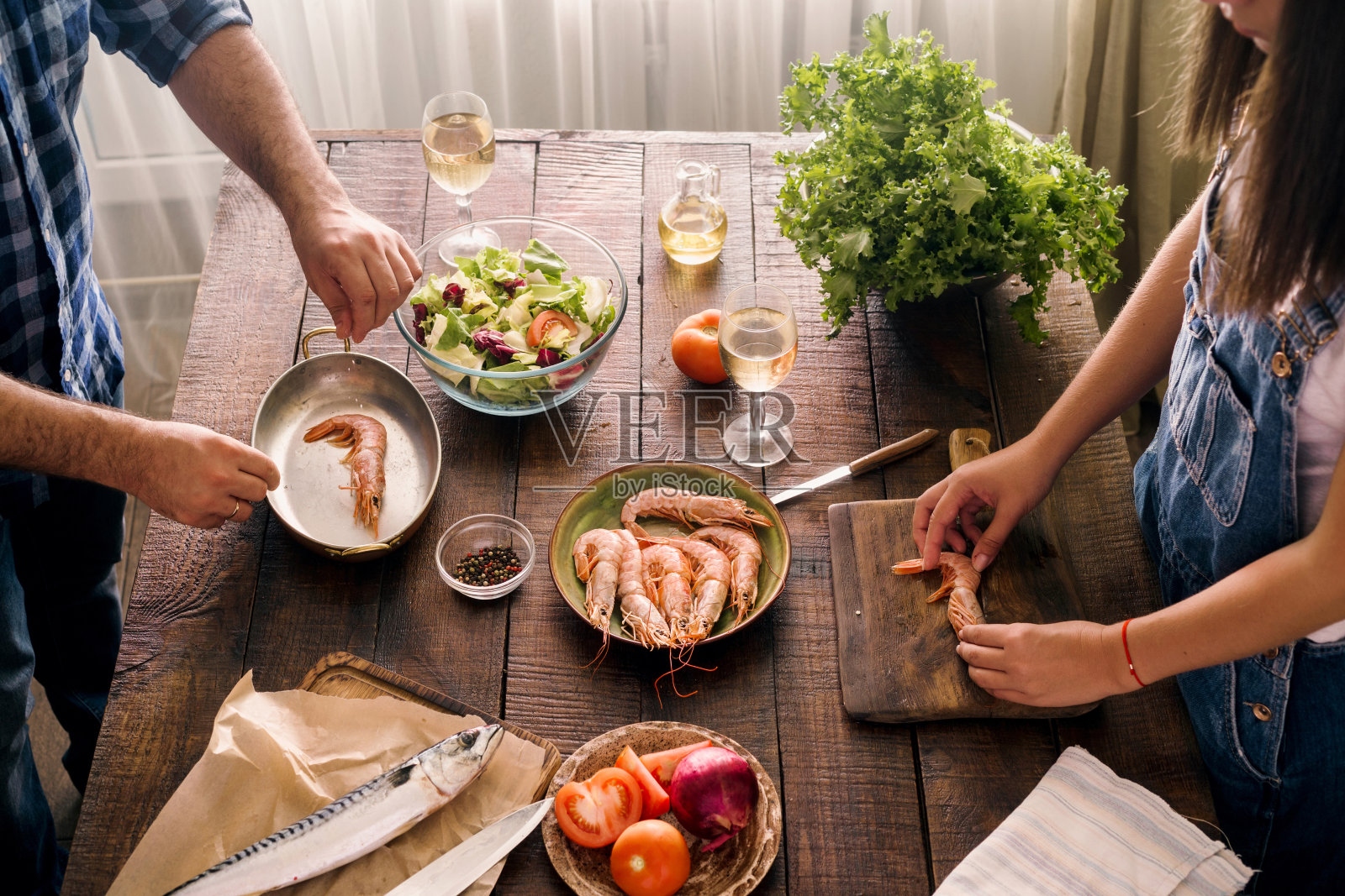 一对夫妇在家庭厨房的木桌上一起烹饪虾晚餐和蔬菜沙拉，俯视图照片摄影图片