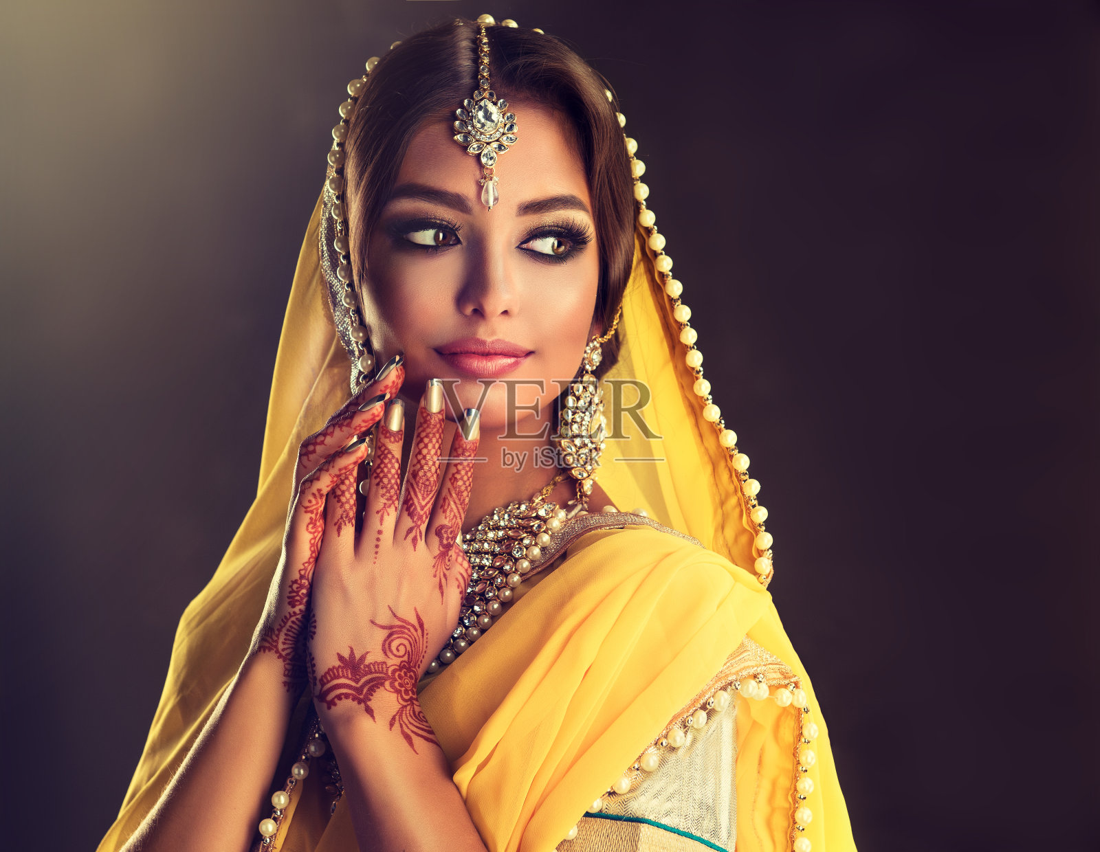 美丽的印度女孩的肖像穿着传统民族服装和曼海蒂纹身在她的手上。照片摄影图片