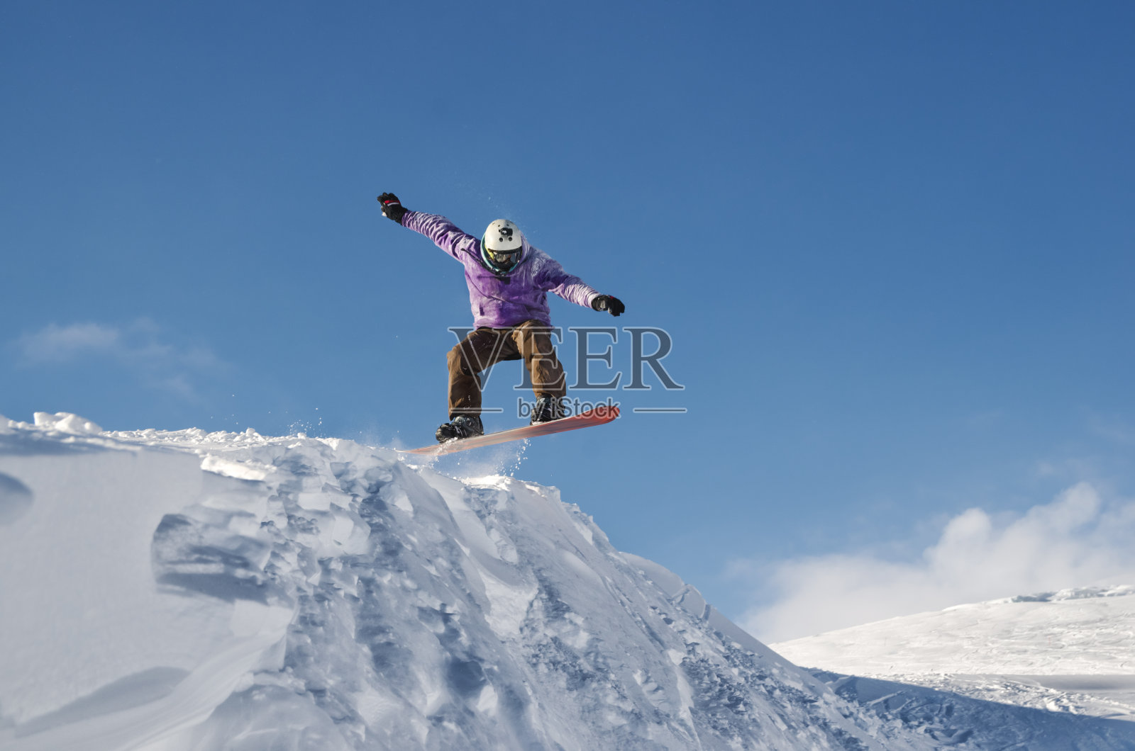 戴着头盔和面具的时尚滑雪板从高雪坡上跳下来照片摄影图片