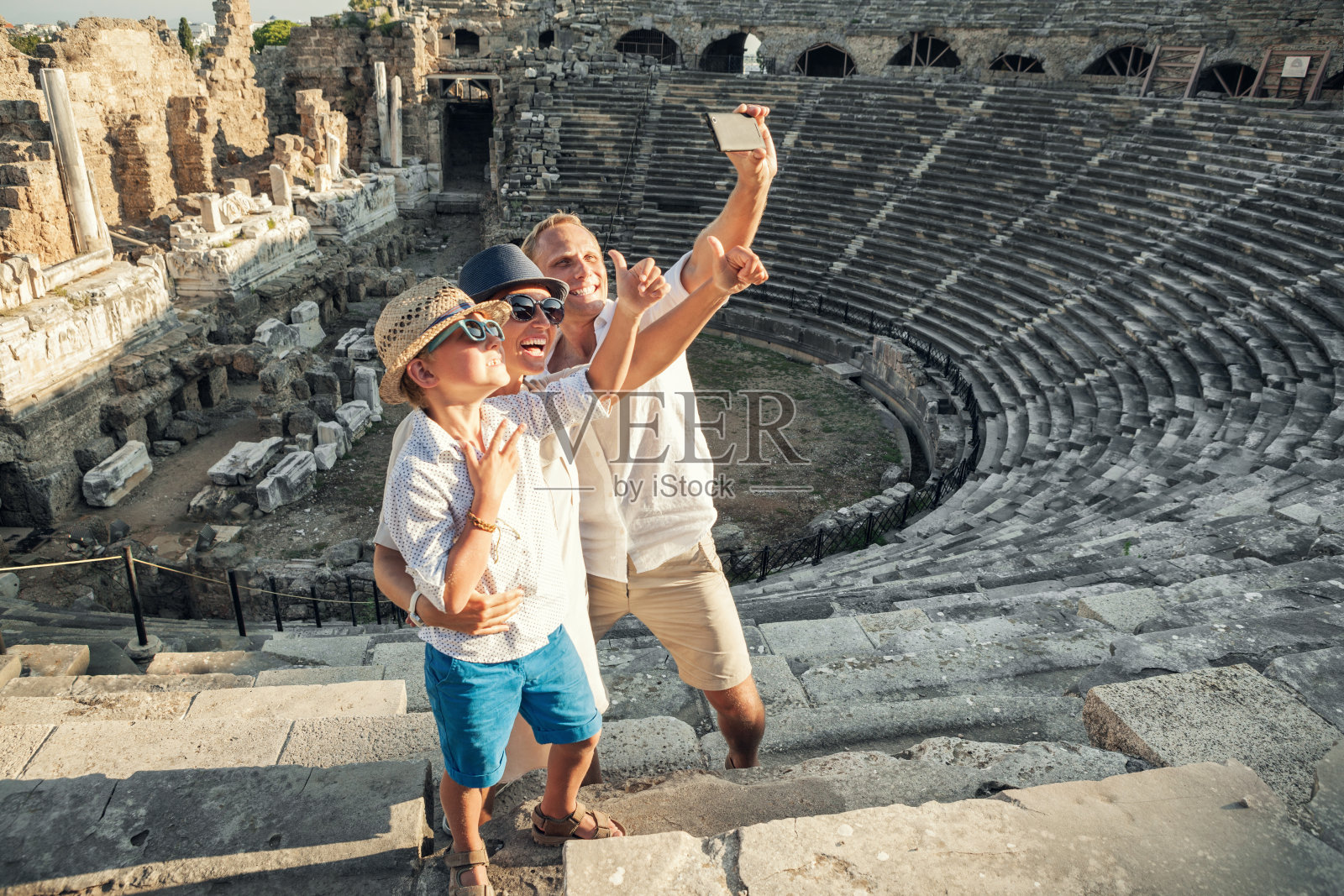 年轻积极的家庭在土耳其赛德的古老的圆形剧场自拍照片摄影图片