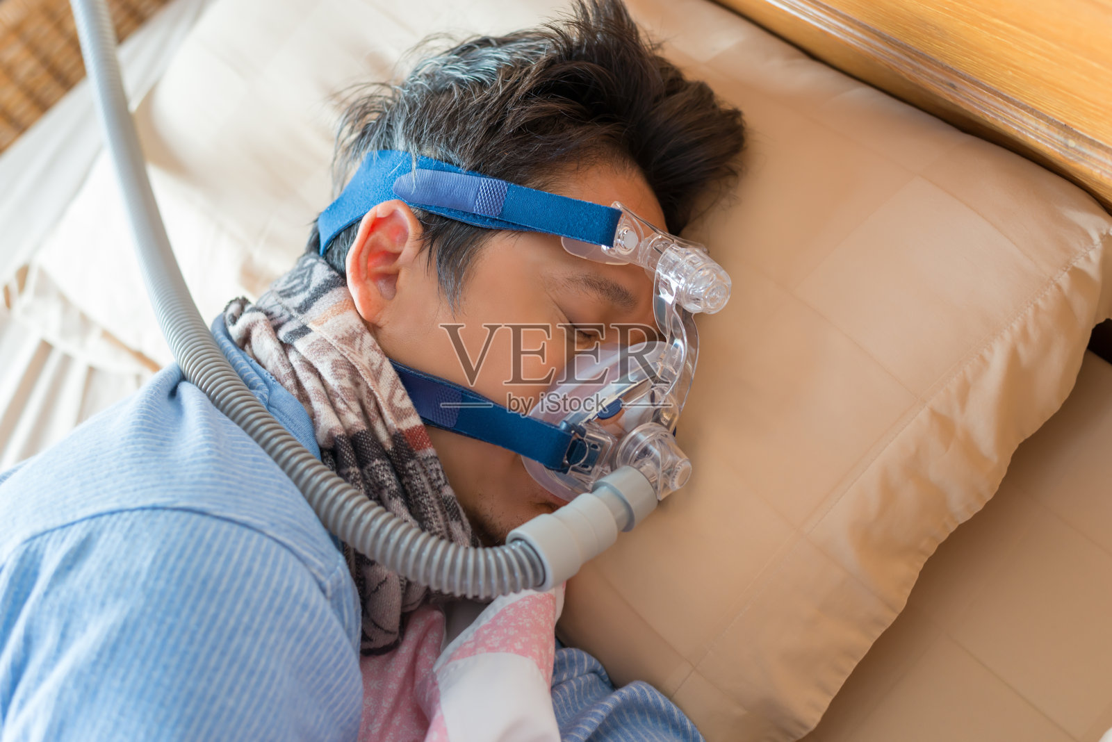 男子侧身躺在床上，戴着CPAP面罩，这是医疗理念。照片摄影图片