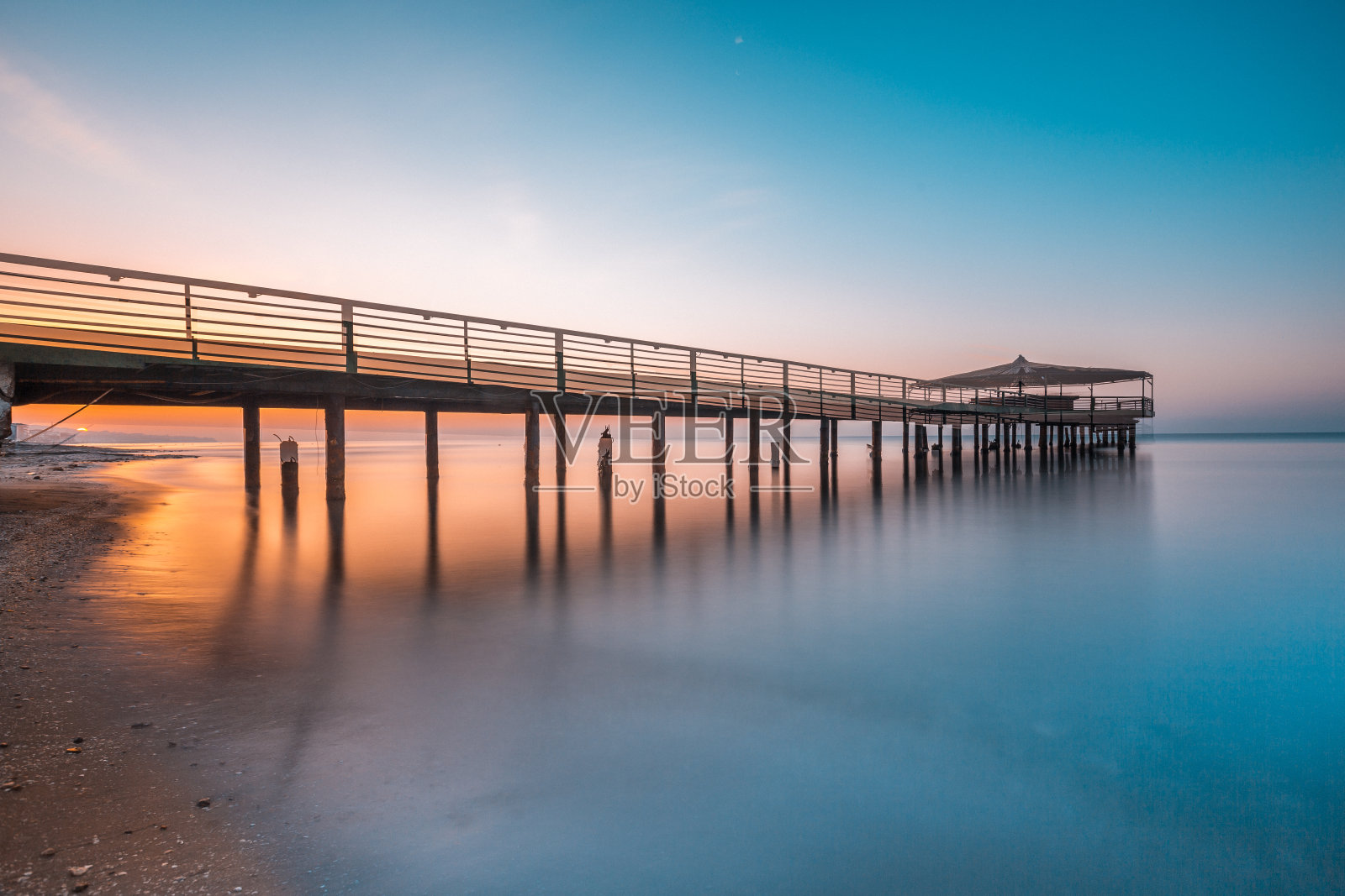 日出时木桥伸向大海照片摄影图片