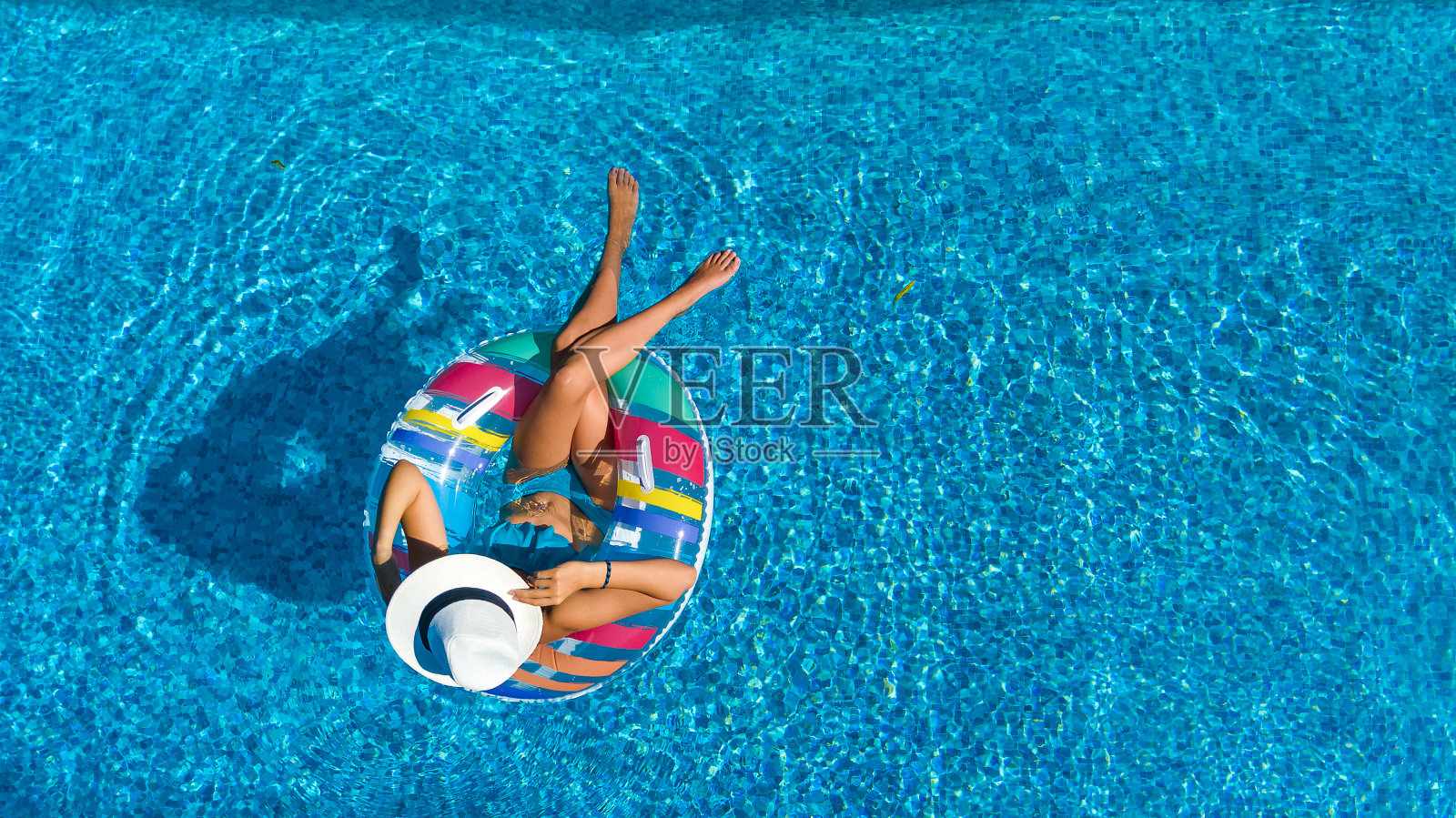 鸟瞰美丽的女孩在游泳池从上面，放松游泳在充气圈甜甜圈和有乐趣的水在家庭度假照片摄影图片