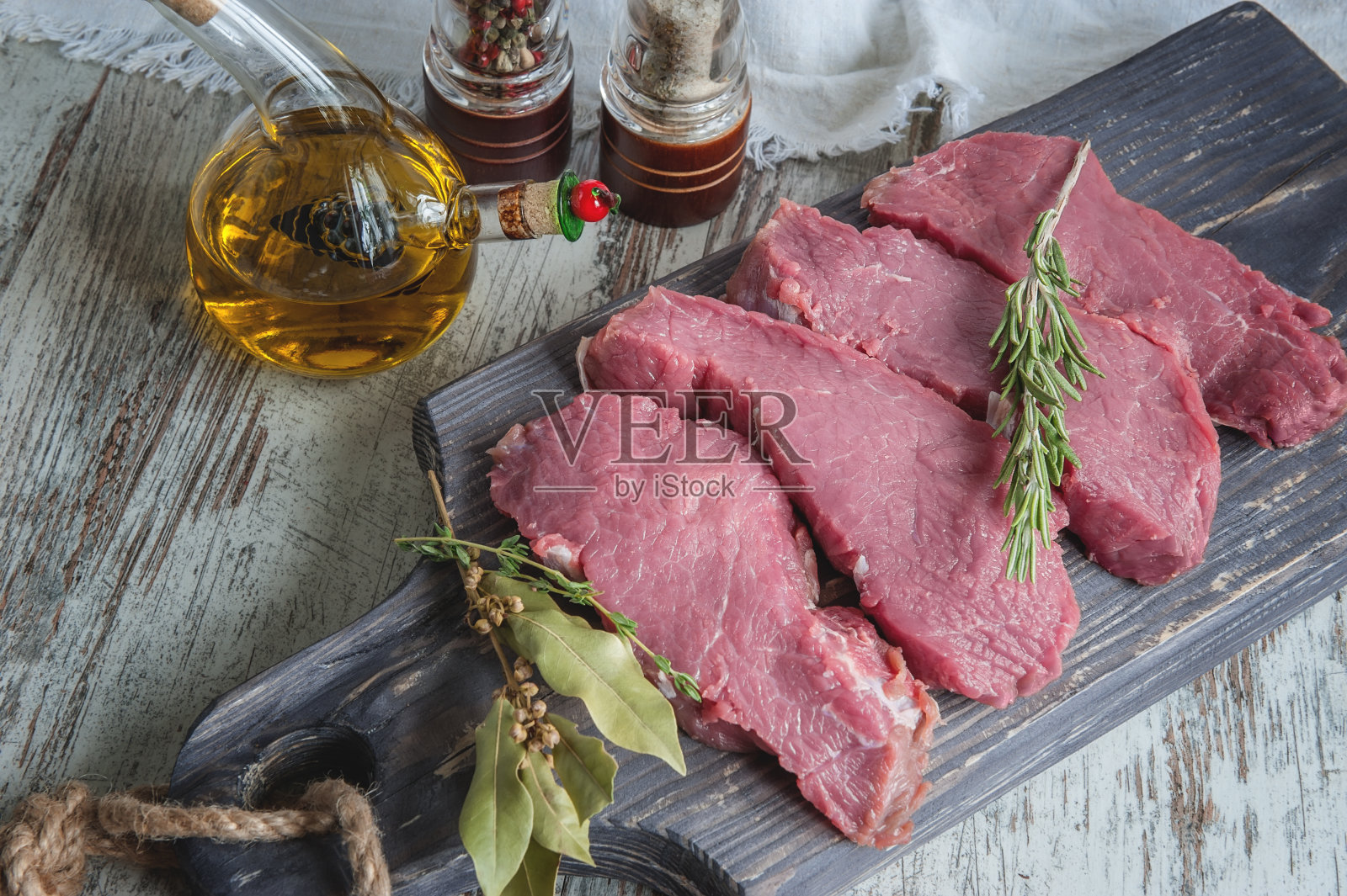 将切好的牛肉放在木砧板上烤，用月桂叶、迷迭香、橄榄油和普罗旺斯香草腌制，以一种乡村风格照片摄影图片
