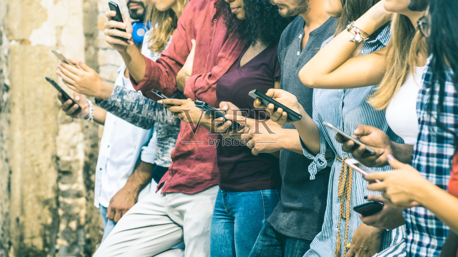 一群多文化的朋友使用智能手机在户外-人们的手沉迷于移动智能手机-与连接的男性和女性的技术概念-浅景深的老式滤镜色调照片摄影图片