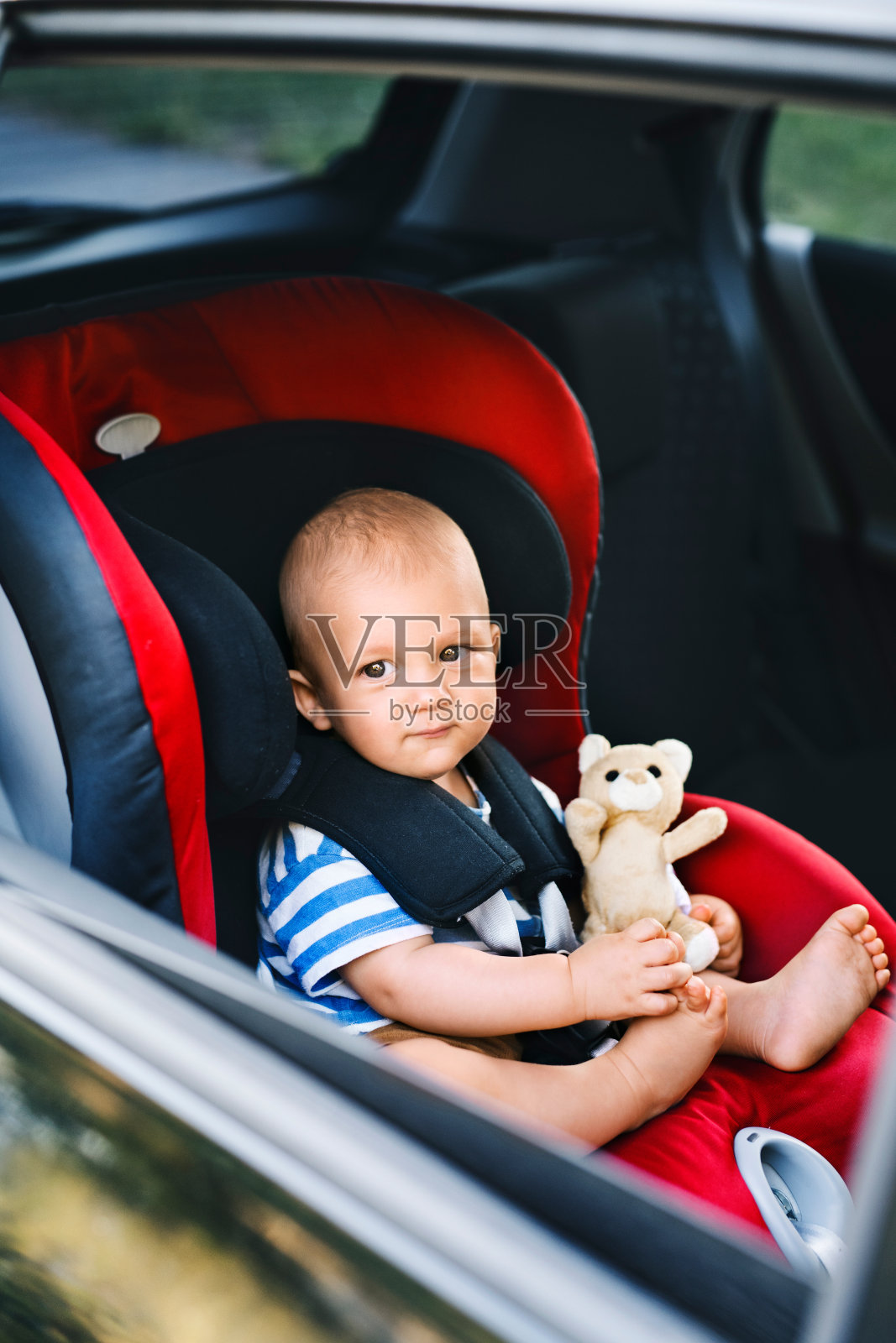 小男孩坐在车里的座椅上。照片摄影图片