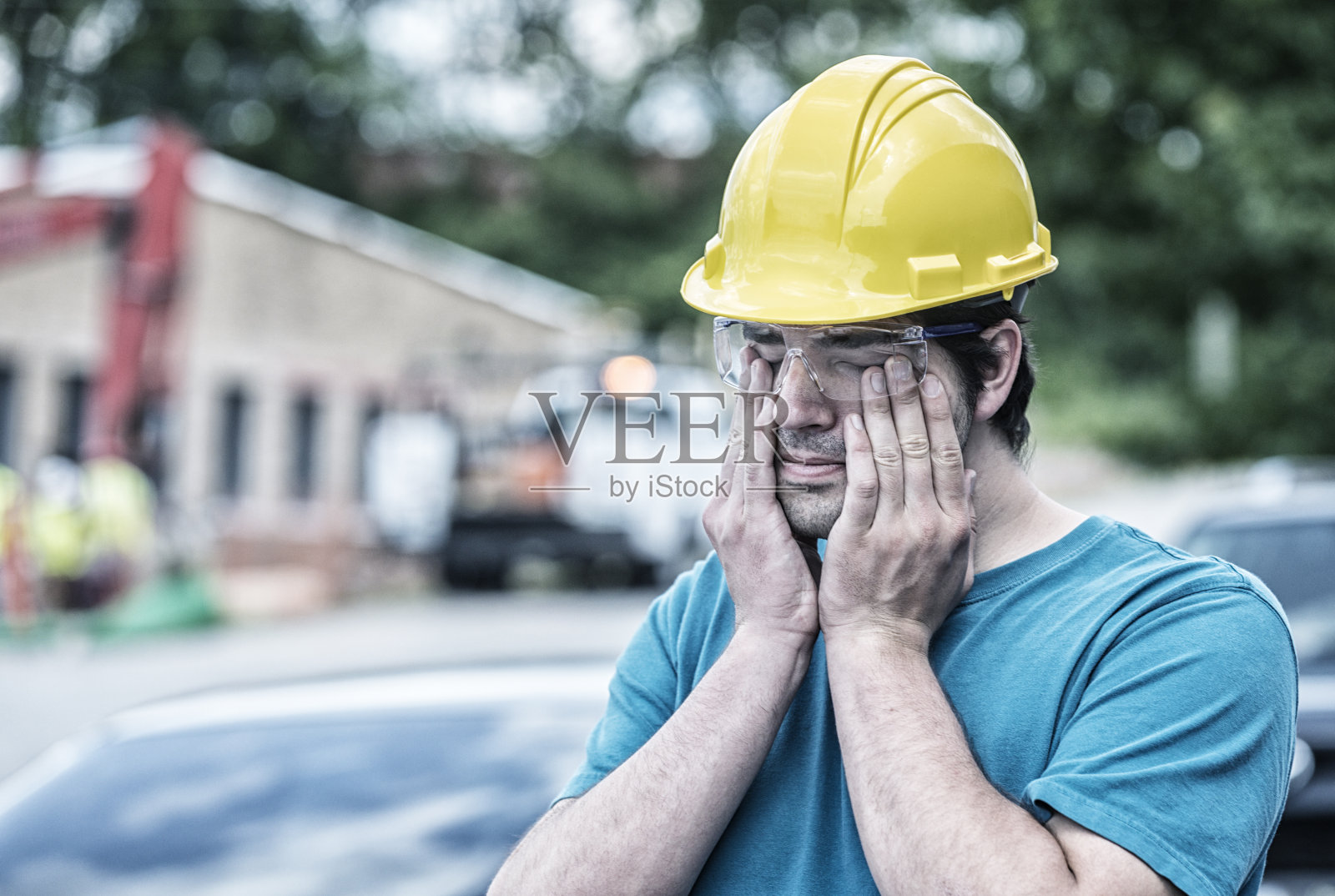 疲惫的年轻人蓝领建筑工人揉他的眼睛照片摄影图片